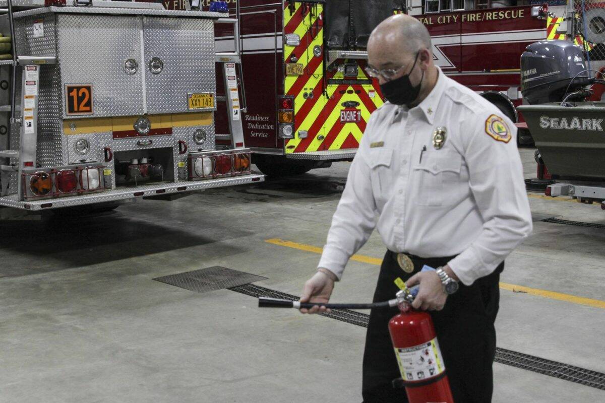 Capital City Fire/Rescue fire marshal Dan Jager demonstrates the proper stance for use of a fire extinguisher on Oct. 30, 2020. Jager had a number of winter safety tips for residents. (Michael S. Lockett / Juneau Empire File)