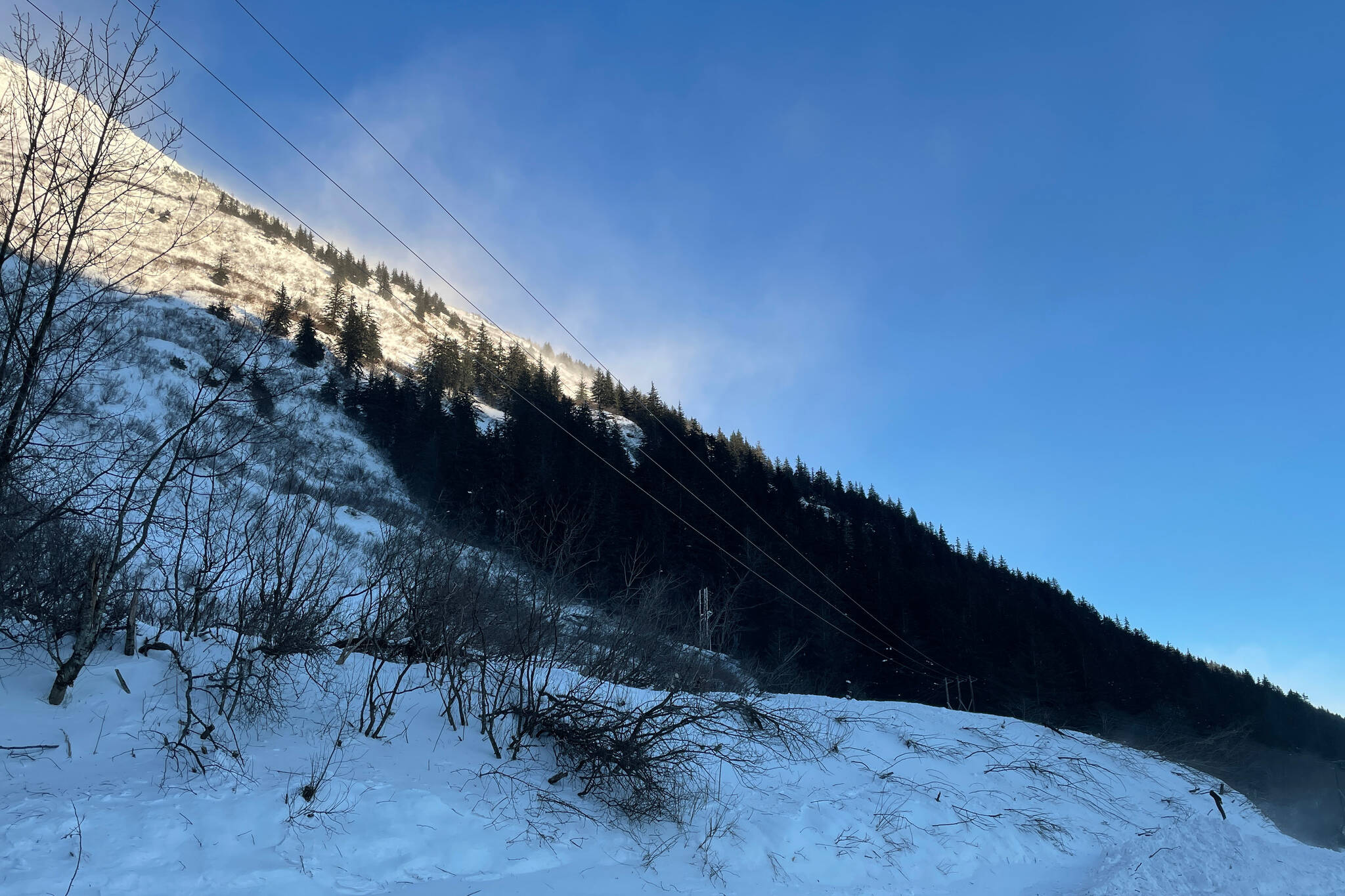 Snow blows off Mount Roberts high above the Thane avalanche chute, where an avalanche blew across the road during a major snowstorm last weekend. (Michael S. Lockett / Juneau Empire)