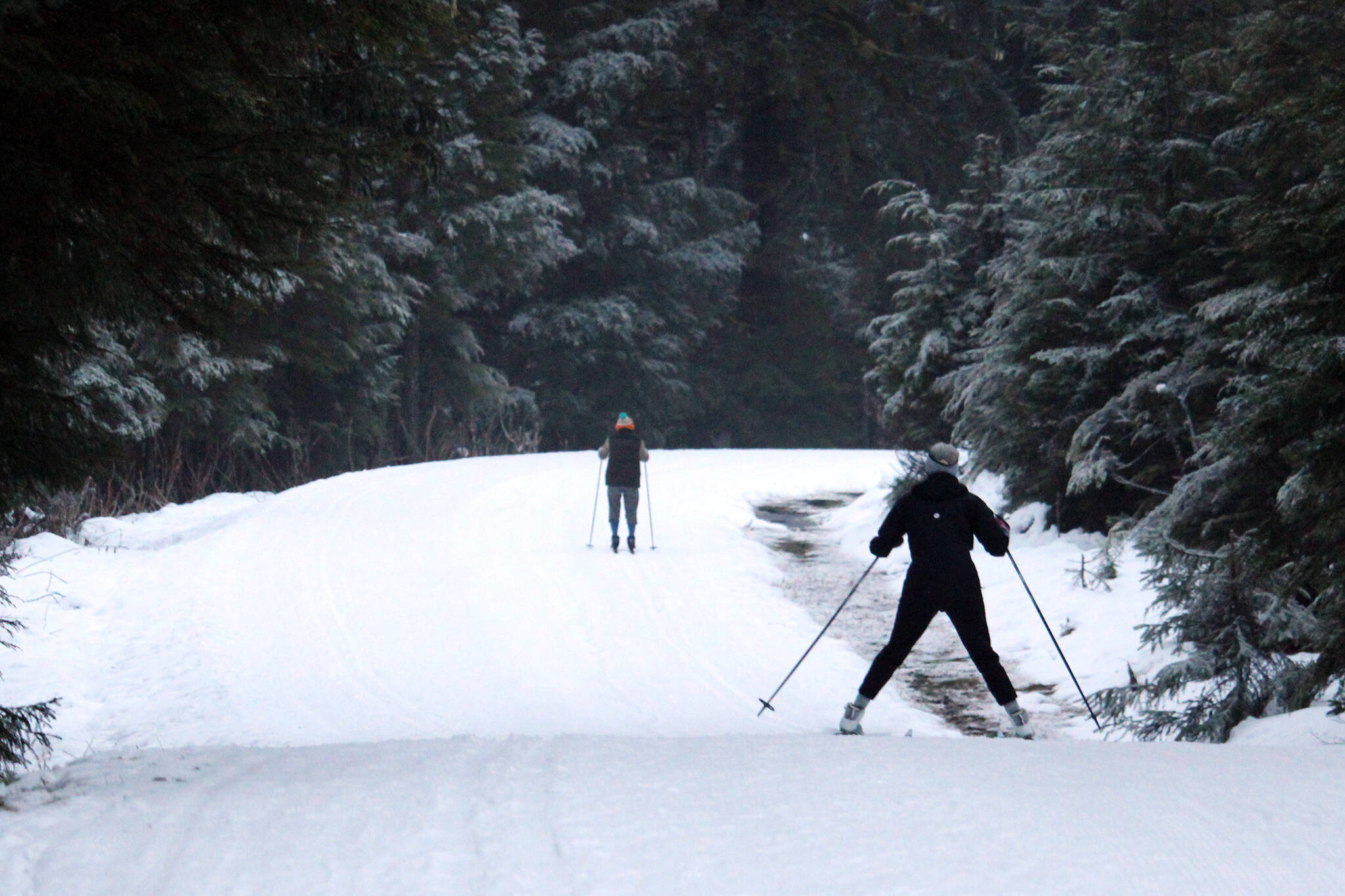 Two skiers make their way down Montana Creek Trail in this December 2020 photo. The groomed trail allows for snowy strolling. (Ben Hohenstatt / Juneau Empire File)