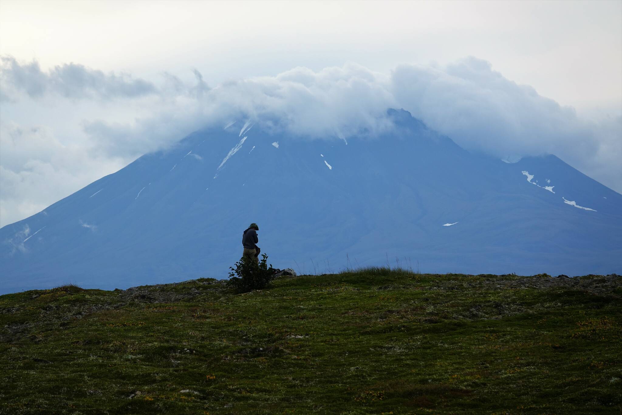 A hiker pauses beneath the volcano Mount Peulik on the Alaska Peninsula. (Courtesy Photo / Bjorn Dihle)
