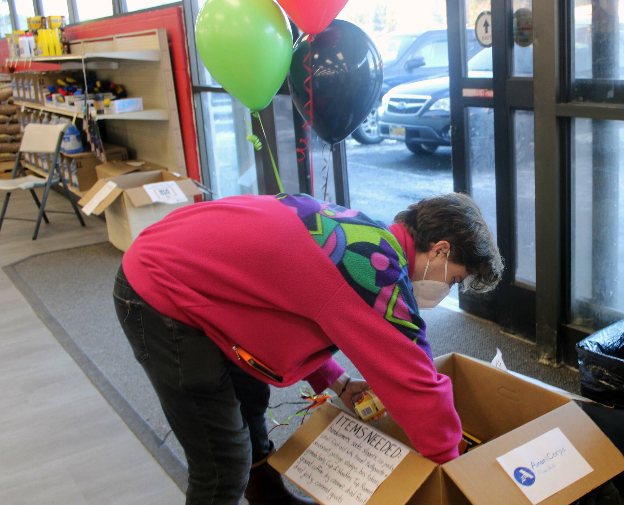 Abe Lahr, an AmeriCorps member, adds donations to the collection box at Super Bear on Jan. 17. Lahr was part of a team that collected food and household items in honor of Martin Luther King Jr. Day. (Dana Zigmund/Juneau Empire)