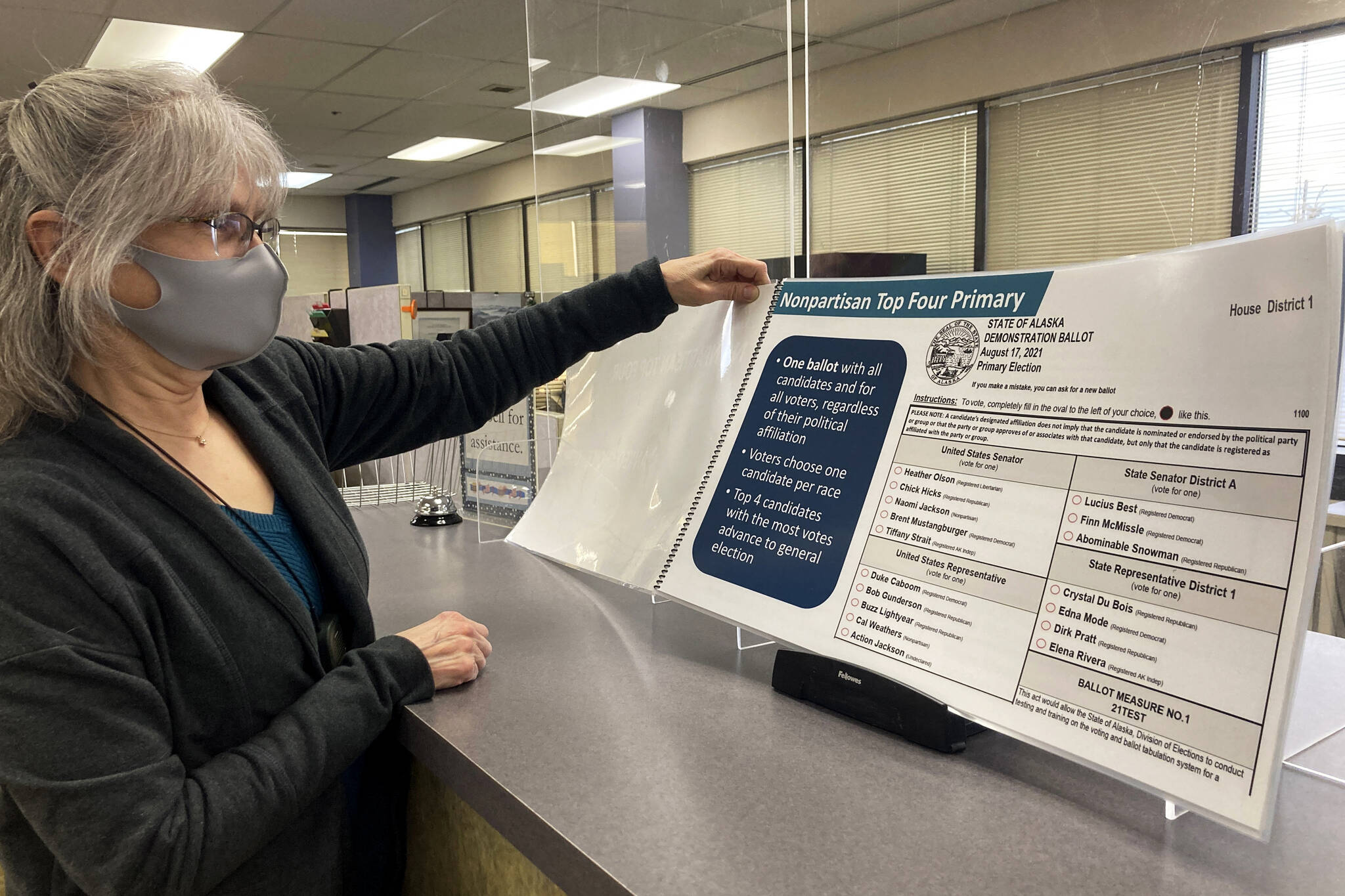 Deborah Moody, an administrative clerk at the Alaska Division of Elections office in Anchorage, Alaska, looks at an oversized booklet explaining election changes in the state on Jan. 21, 2022. Alaska elections will be held for the first time this year under a voter-backed system that scraps party primaries and sends the top four vote-getters regardless of party to the general election, where ranked choice voting will be used to determine a winner. No other state conducts its elections with that same combination. (AP Photo / Mark Thiessen)