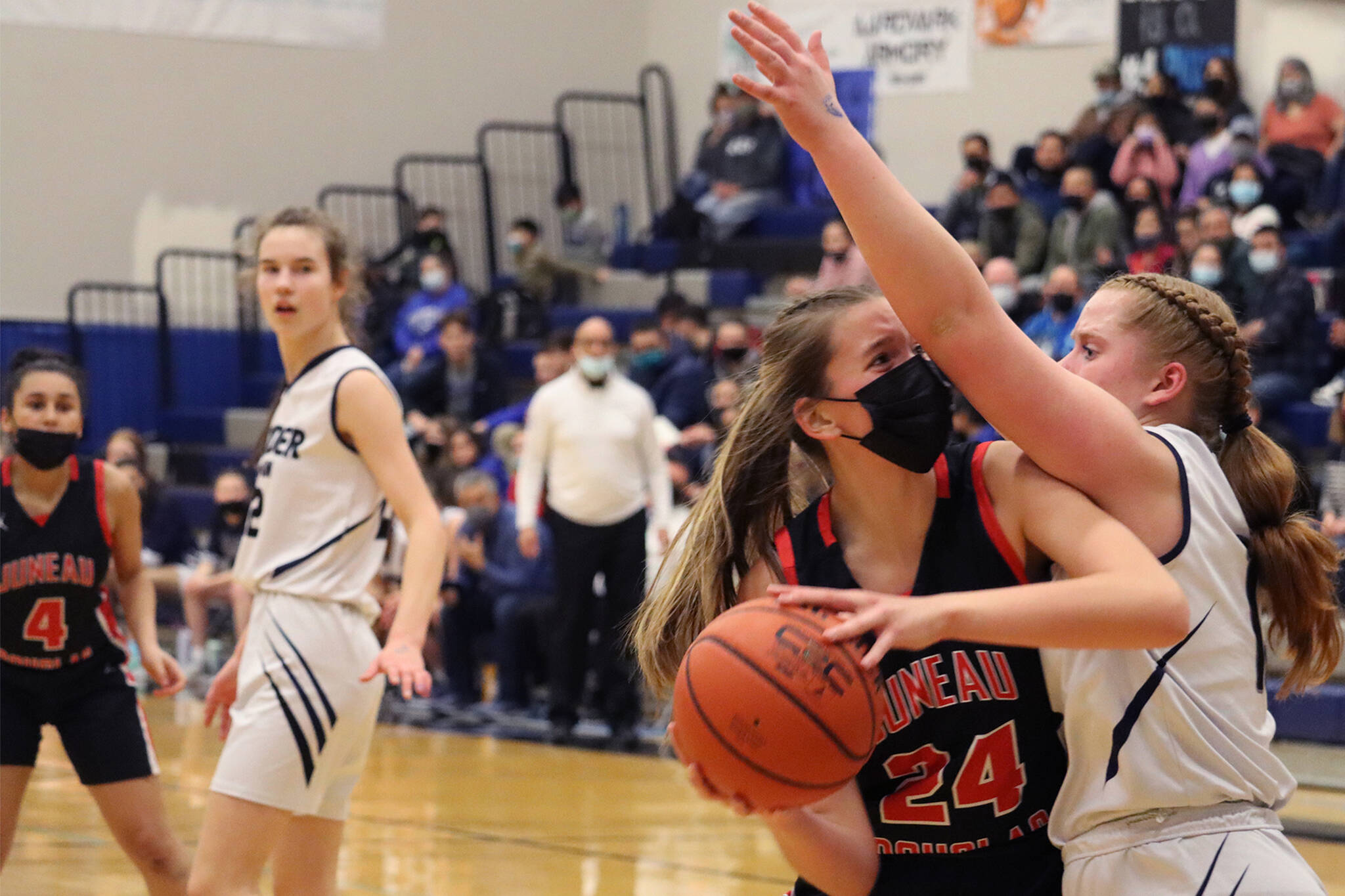 JDHS’ Mila Hargrave pivots toward the hoop for a tough inside shot while tightly defended by TMHS’ Sydney Strong. In the background JDHS’ Kiyara Miller and TMHS’ Kerra Baxter look on. (Ben Hohenstatt / Juneau Empire)