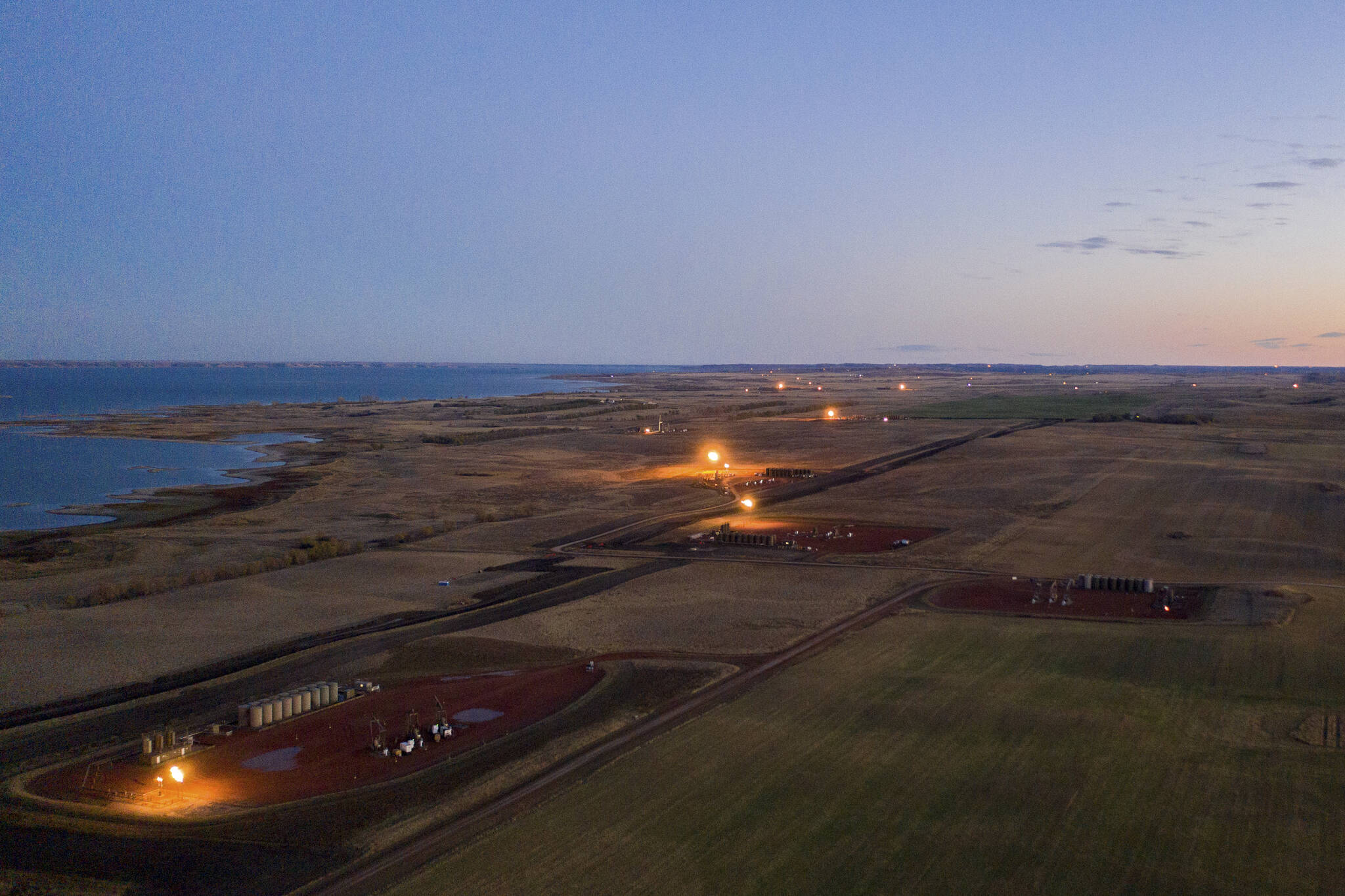 Flares light up the landscape after sunset on the oil patch in the Fort Berthold Indian Reservation in North Dakota on Oct. 27, 2021. Over much of the last decade, oil and gas operators in Texas and a dozen other U.S. states have flared, or burned off, at least 3.5 trillion cubic feet of natural gas, according to an analysis of satellite data by the Howard Center for Investigative Journalism. (Isaac Stone Simonelli / Howard Center for Investigative Journalism)