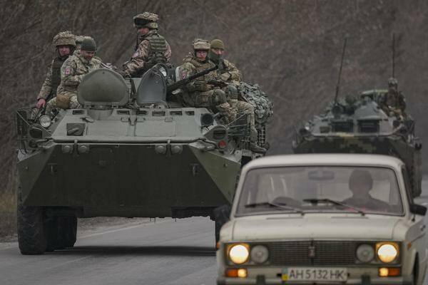 Ukrainian servicemen sit atop armored personnel carriers driving on a road in the Donetsk region, eastern Ukraine, Thursday, Feb. 24, 2022. (AP Photo/Vadim Ghirda)