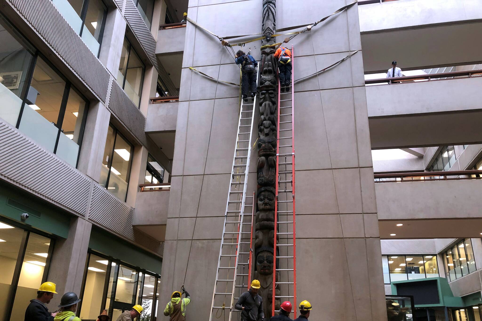 Peter Segall / Juneau Empire 
The Wooshkeetaan Kootéeyaa totem pole was re-installed at its new home in the attrium of the State Office Building on Friday, March 11, 2022. Workers from Alaska Electric Light and Power helped install the pole.