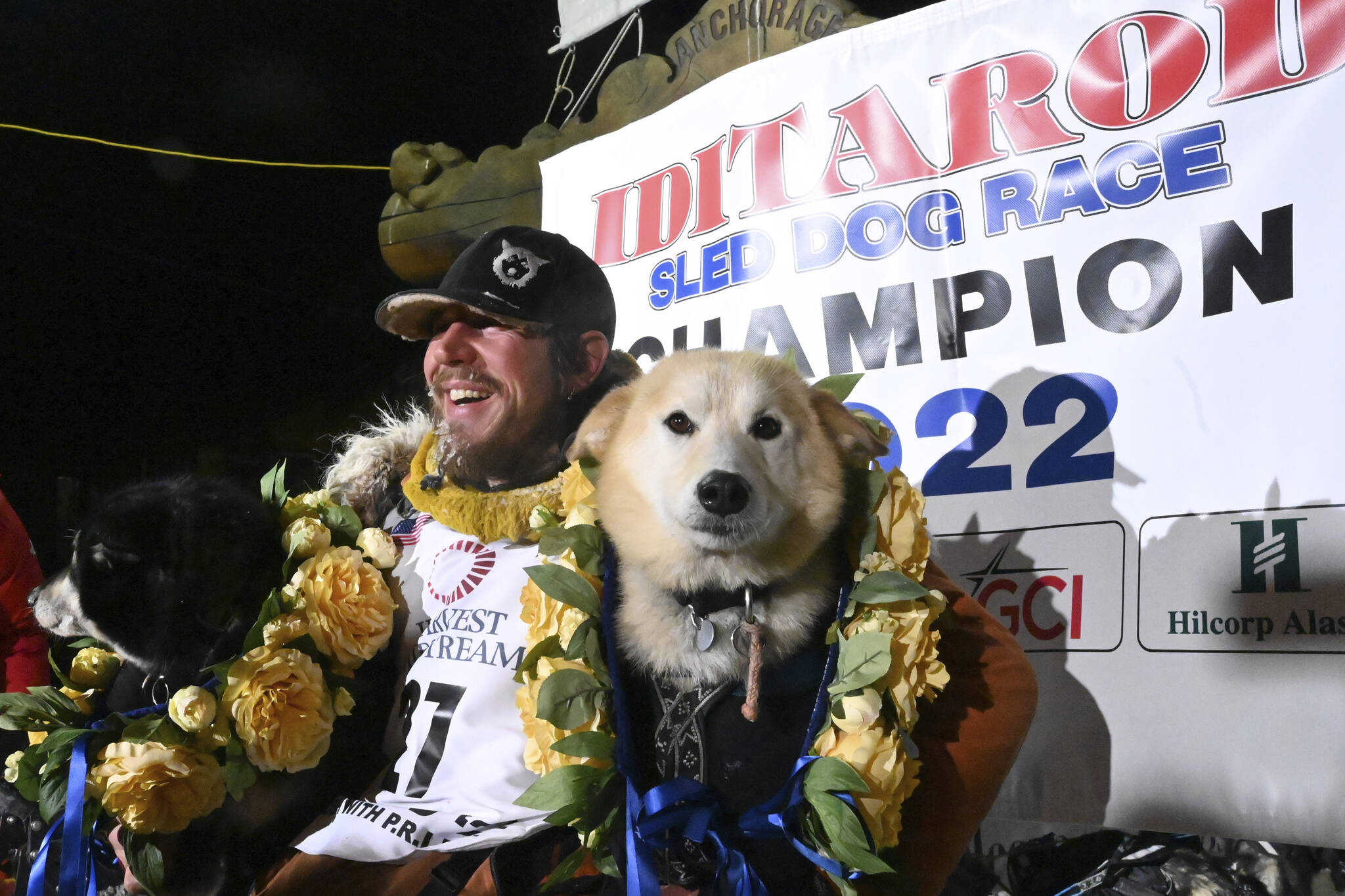 Iditarod winner Brent Sass poses for photos with lead dogs Morello, left, and Slater in the finish chute of the Iditarod Trail Sled Dog Race in Nome, Alaska, Tuesday March 15, 2022. (Anne Raup / Anchorage Daily News)