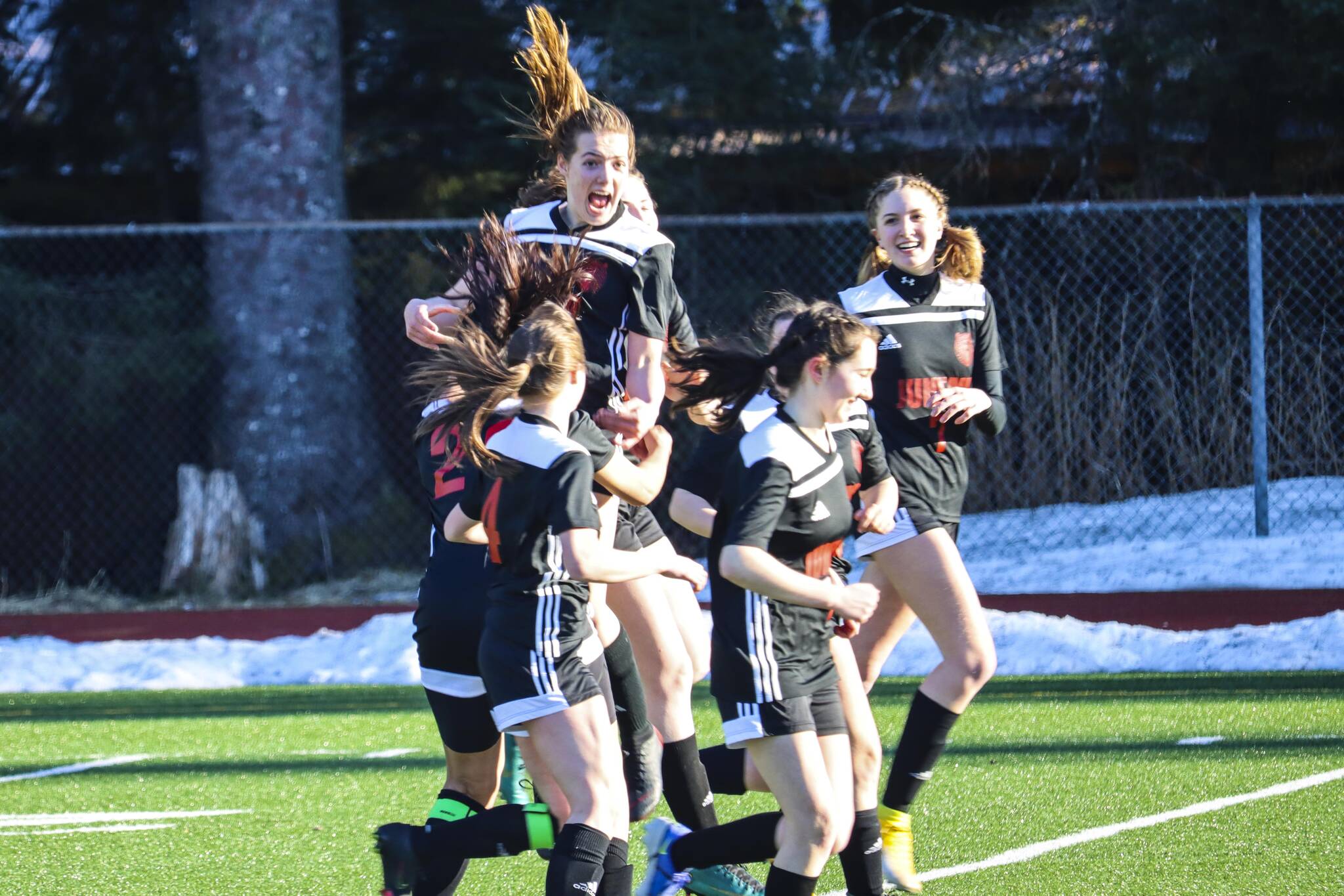 JDHS forward Kyla Bentz, top center, celebrates with her team after scoring on TMHS during a game at Adair-Kennedy Memorial Park on April 12, 2022. (Michael S. Lockett / Juneau Empire)