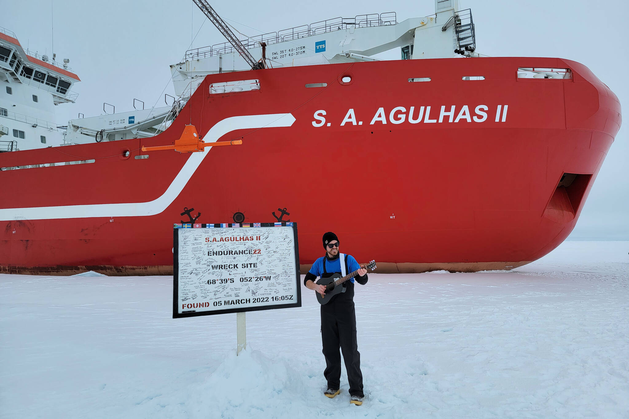 Michael Patz, raised in Juneau, stands on the ice in front of the S.A. Agulhas II next to a sign showing the location of the wreck of Ernest Shackleton’s vessel, the Endurance, rediscovered by searchers aboard the icebreaker. (Courtesy photo / Michael Patz)