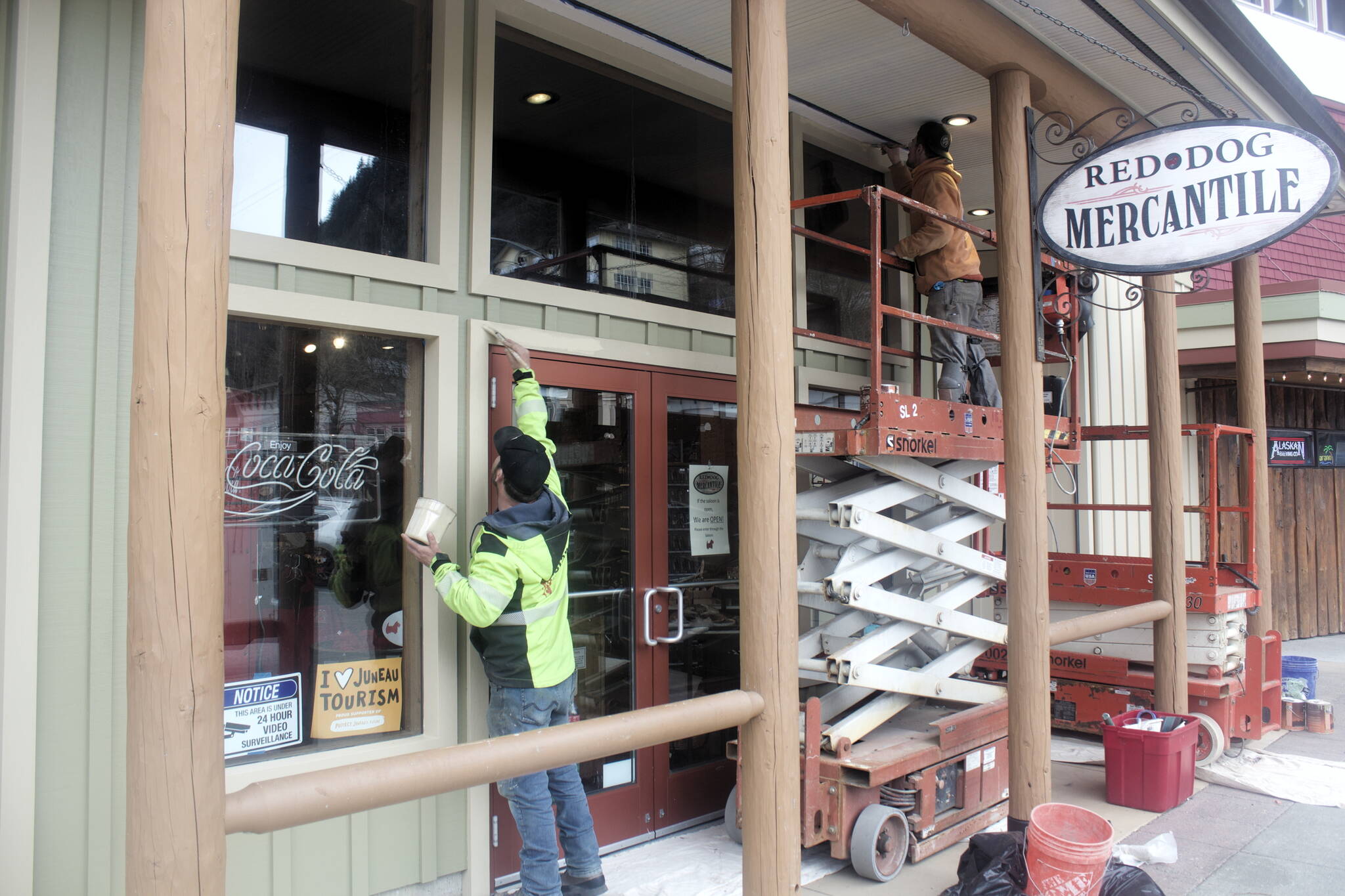 Kyle Brownlee, left, and Joseph Cox of Island Contractors paint the storefront of Red Dog Mercantile on Friday as downtown merchants get ready to welcome the first cruise ship of the year on Monday. (Mark Sabbatini / Juneau Empire)