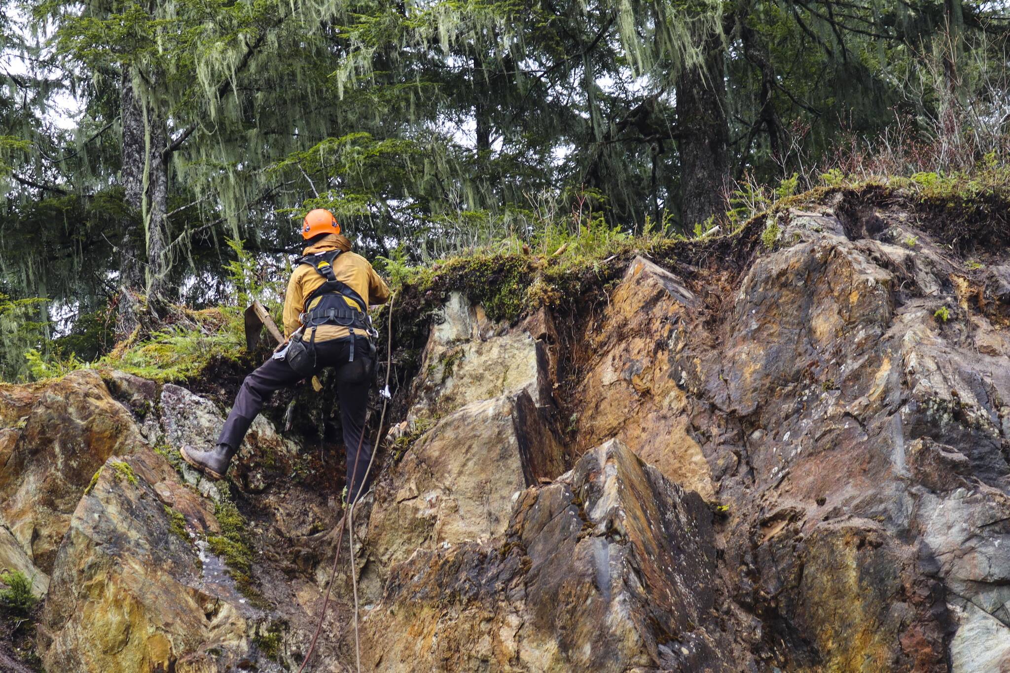 Clint Helander of Advanced Blasting Services clears remaining material from a cliffside near the University of Alaska Southeast student recreation center that had a substantial rockslide in February. (Michael S. Lockett / Juneau Empire)