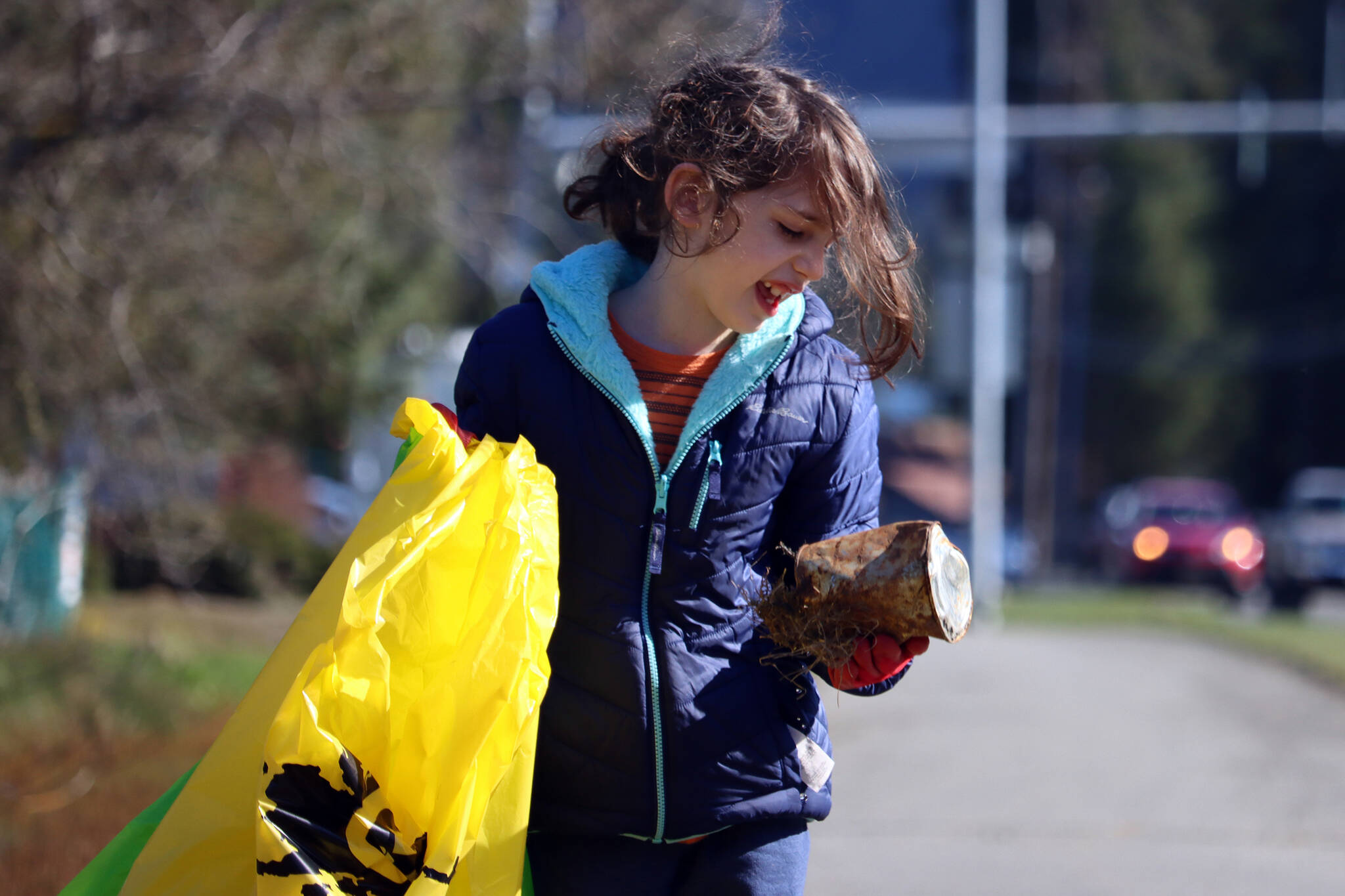 Gerald Thill, 7, inspects a weathered can before placing it in a litter bag on Saturday during the citywide cleanup. (Ben Hohenstatt / Juneau Empire)
