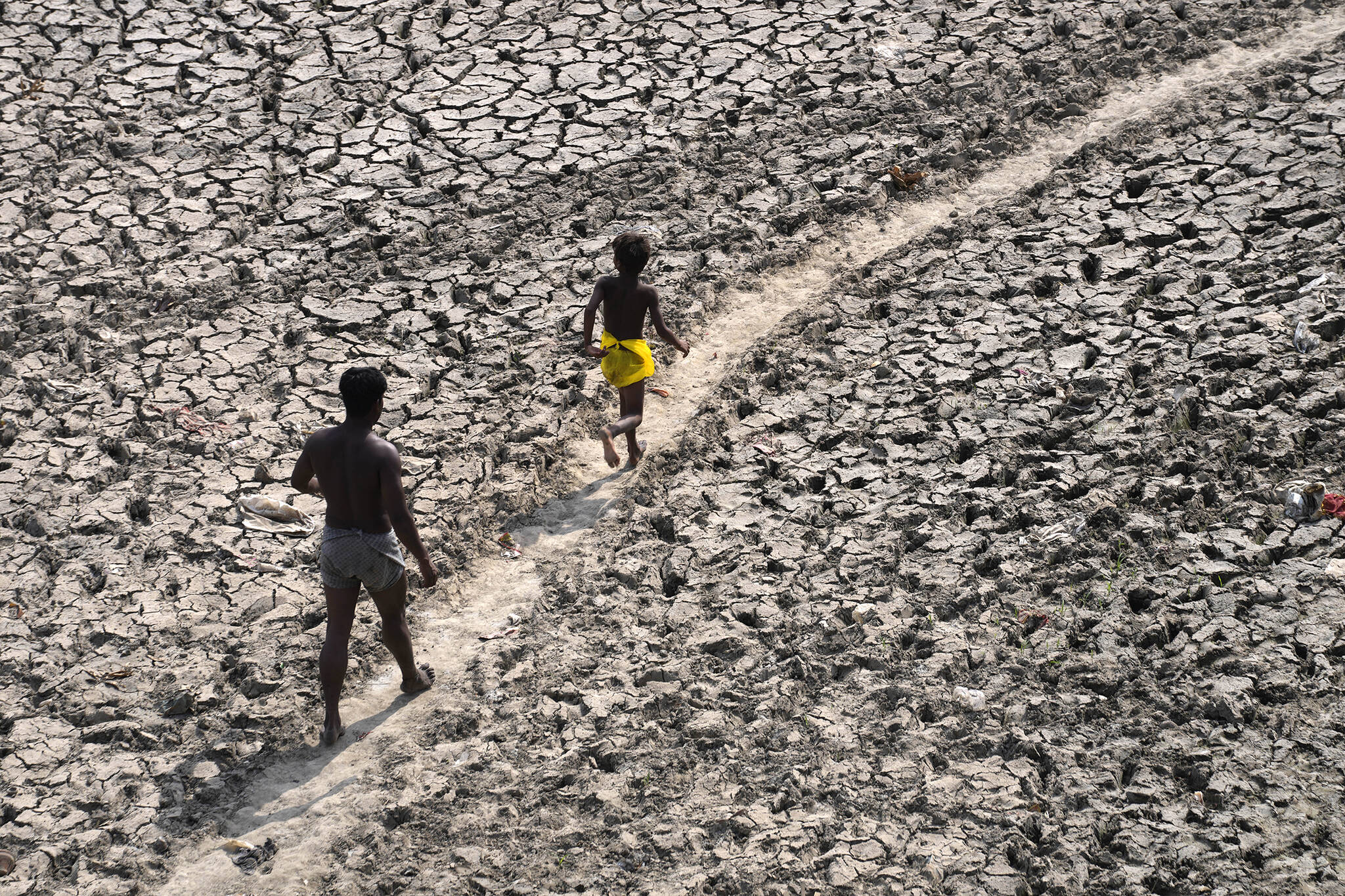 A man and a boy walk across the almost dried up bed of river Yamuna following hot weather in New Delhi, India, Monday, May 2, 2022. According to a report released by the World Meteorological Organization on Monday, May 9, 2022, the world is creeping closer to the warming threshold international agreements are trying to prevent, with nearly a 50-50 chance that Earth will temporarily hit that temperature mark within the next five years. (AP Photo / Manish Swarup)