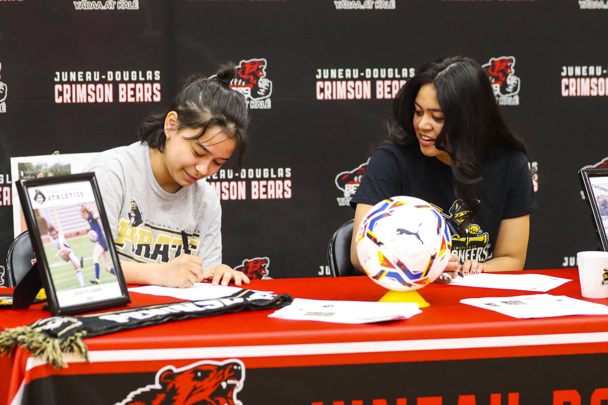 Blake Plummer, left, and Sophia Pugh, both JDHS girls soccer players, sign their letters of intent to play for Peninsula College and the Pratt Institute respectively on May 9, 2022. (Michael S. Lockett / Juneau Empire)