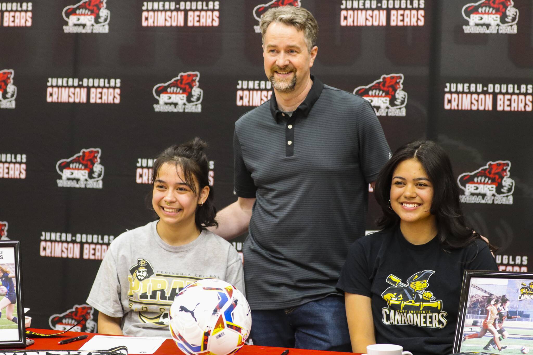 JDHS girls soccer coach Matt Dusenberry poses with Blake Plummer, left, and Sophia Pugh who just signed their letters of intent to play college soccer at separate schools May 9, 2022. (Michael S. Lockett / Juneau Empire)