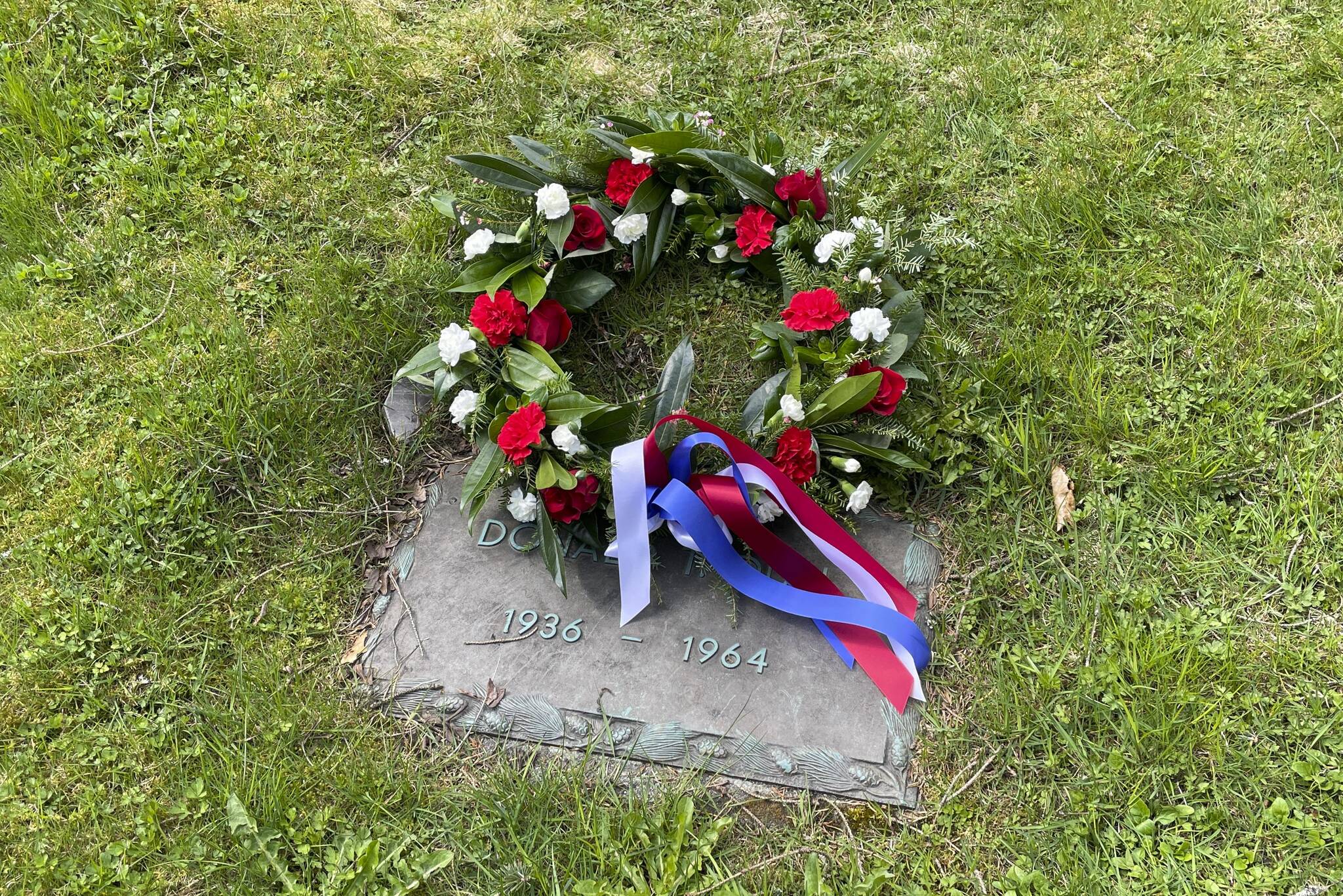 A wreath is laid on the grave of Donald T. Dull, a Juneau police officer killed on duty in 1964, during a Peace Officers Memorial Day ceremony at Evergreen Cemetery on May 13, 2022. (Michael S. Lockett / Juneau Empire)