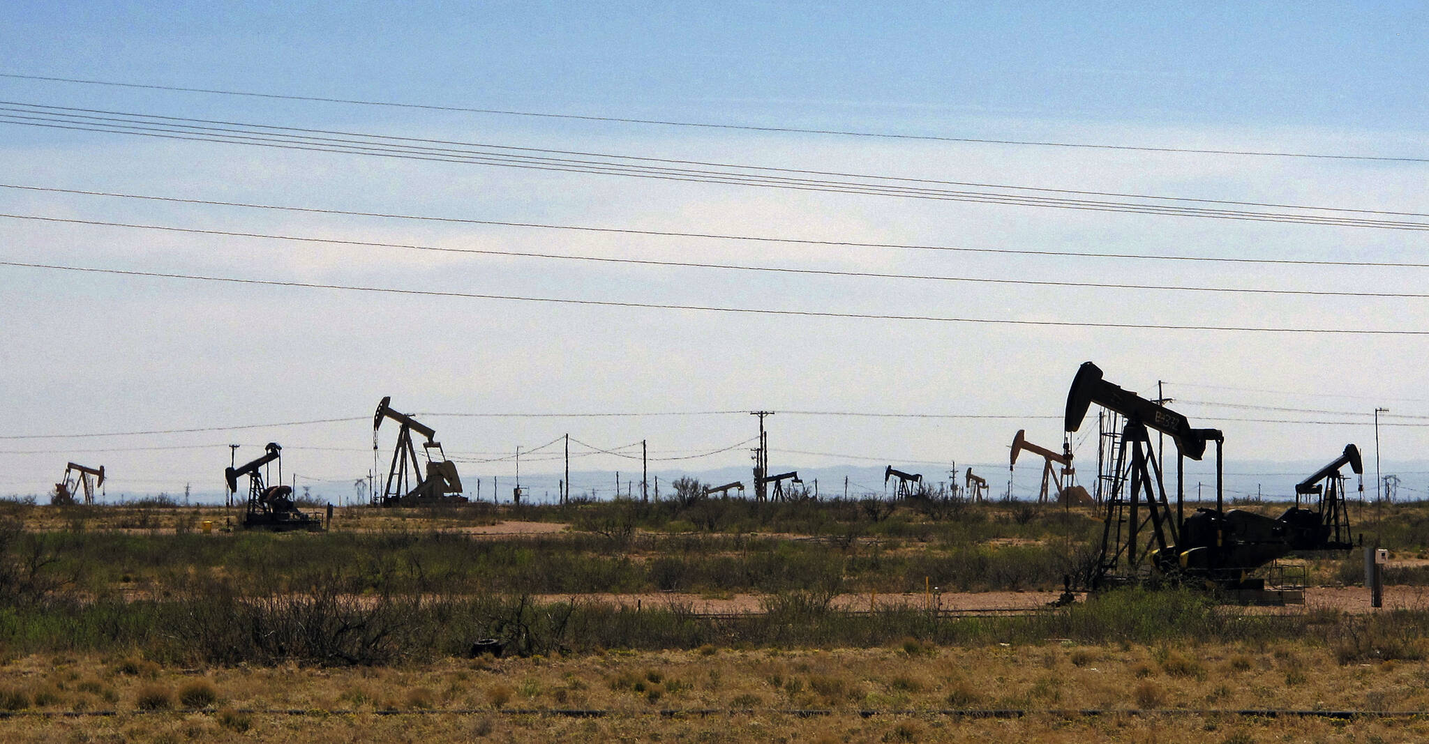 Oil rigs stand in the Loco Hills field along U.S. Highway 82 in Eddy County, near Artesia, N.M., one of the most active regions of the Permian Basin. Government budgets are booming in New Mexico. The reason behind the spending spree — oil. New Mexico is the No. 2 crude oil producer among U.S. states and the top recipient of U.S. disbursements for fossil fuel production on federal land. But a budget flush with petroleum cash has a side effect: It also puts the spotlight on how difficult it is for New Mexico and other states to turn their rhetoric on tackling climate change into reality. (AP Photo / Jeri Clausing)