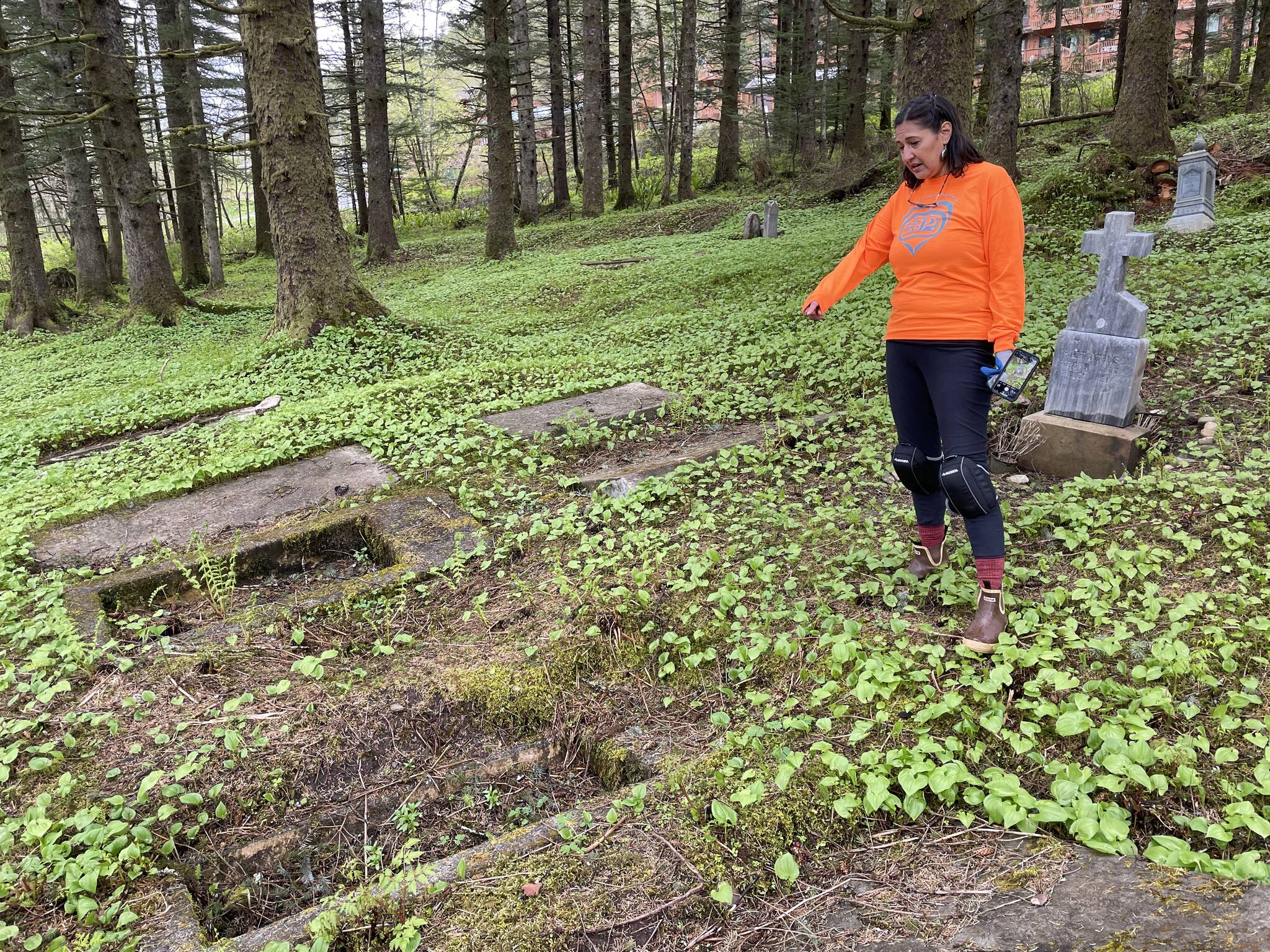 Michael S. Lockett / Juneau Empire 
Jamiann Hasselquist, one of the organizers of the cleanup of the cemetery located near Lawson Creek, gestures to an Alaska Native grave that had long gone neglected on May 14, 2022.