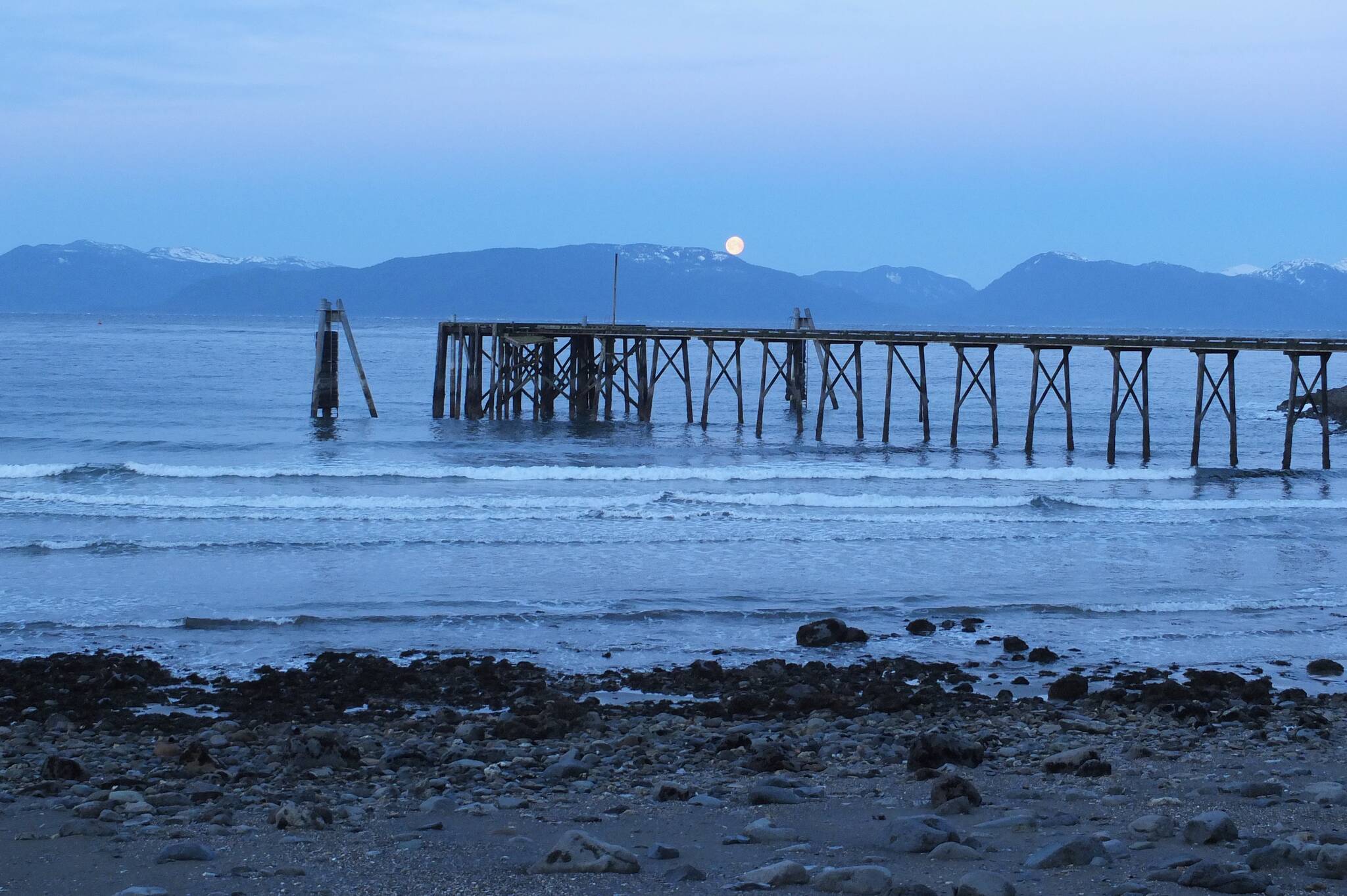 The moon sets over the mountains as seen from an Angoon beach in February of 2015. (Courtesy Photo / Mary Catharine Martin)