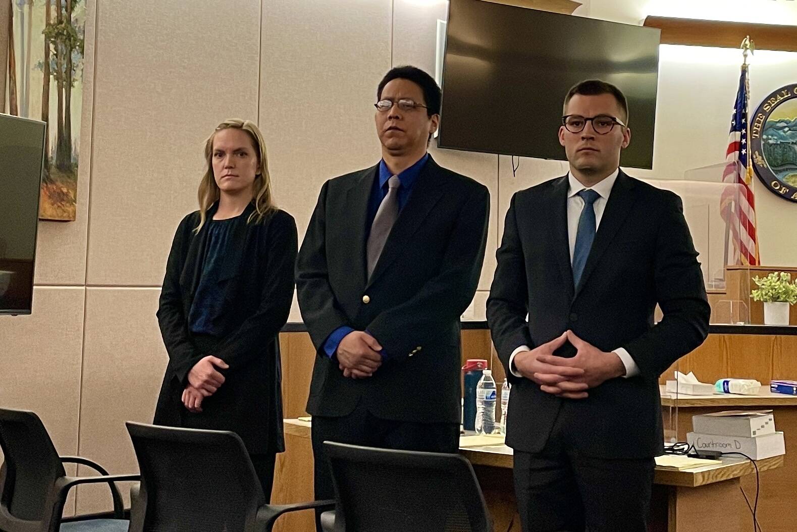 From the left, investigator Emily Chapel, defendant Fenton Jacobs and defense attorney Nicolas Ambrose stand as the jury in Jacobs’ trial enters the courtroom on May 18, 2022. (Michael S. Lockett / Juneau Empire)