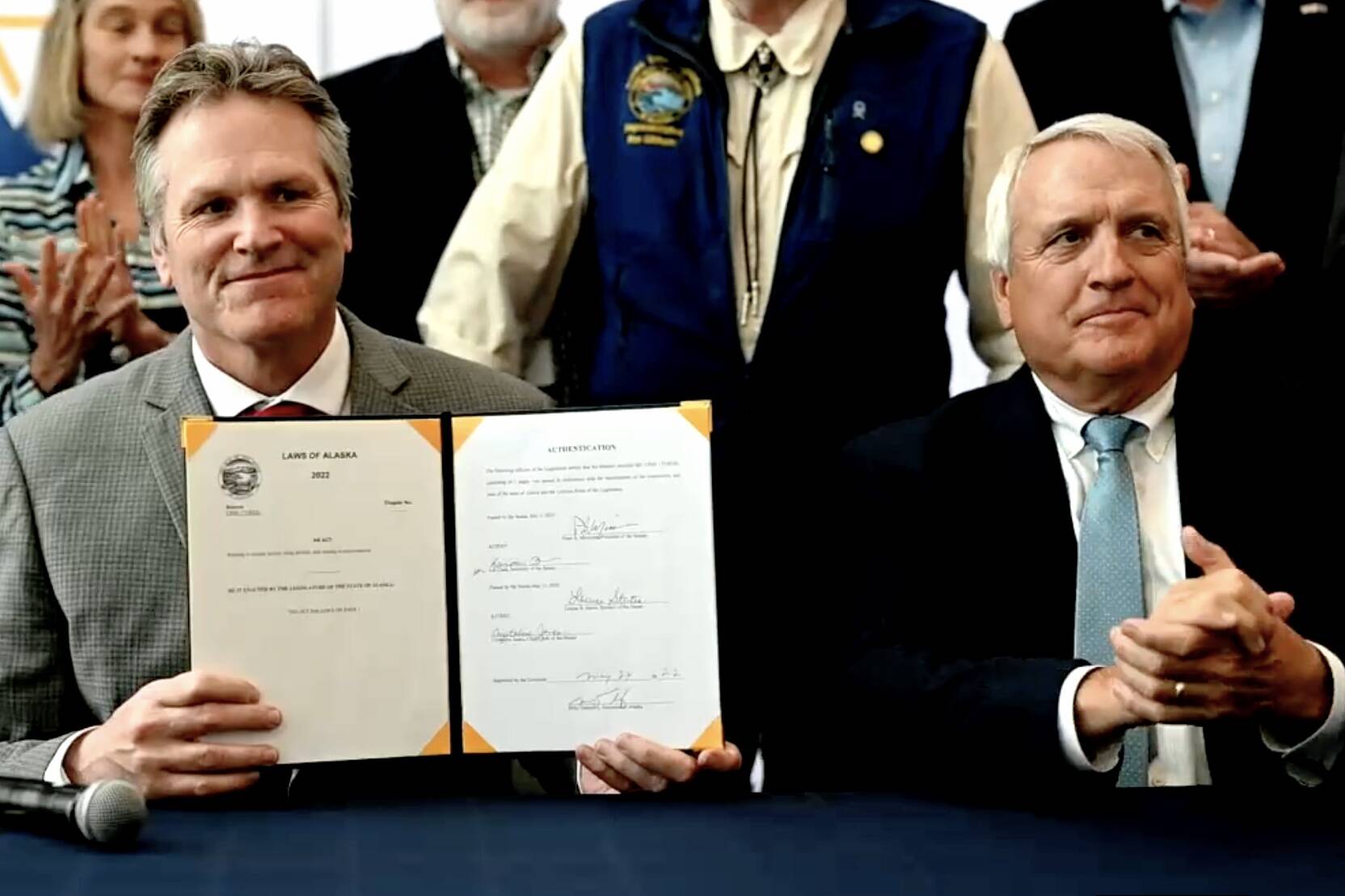Alaska Gov. Mike Dunleavy, left, holds up a copy of Senate Bill 177, easing regulations for nuclear microreactors, with former Colorado Gov. Bill Ritter at the first Alaska Sustainable Energy Conference at the Dena’ina Civic and Convention Center in Anchorage on Tuesday, May 24, 2022. (Screenshot)