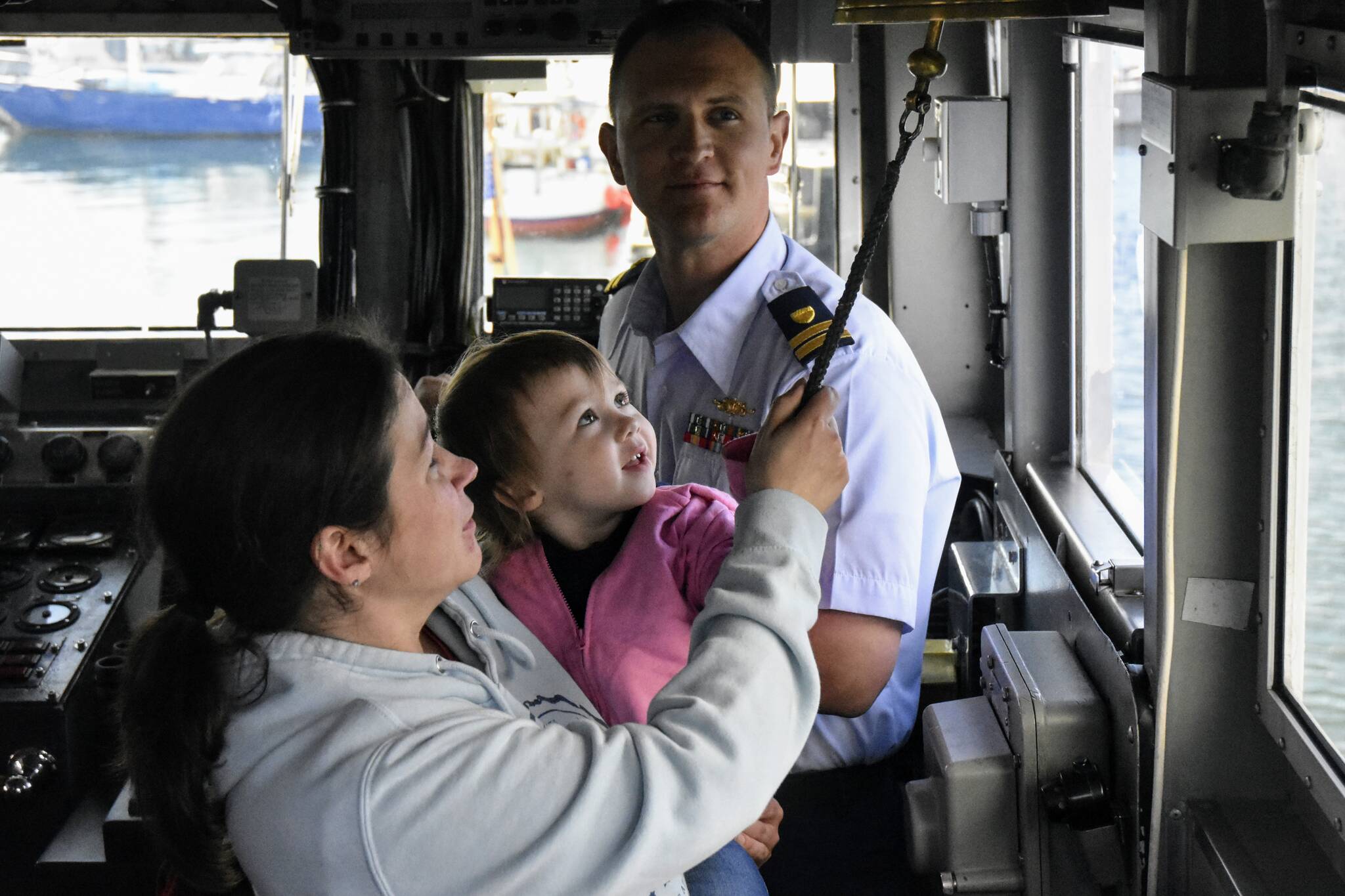 Lt. George Greendyk, commanding officer of the U.S. Coast Guard Liberty, watches as a mother and child ring the bell on the ships bridge on Thursday, May 26, 2022. The Liberty is being re-homeported in Valdez and as a send-off, the ship was open to the public for tours. (Peter Segall / Juneau Empire)