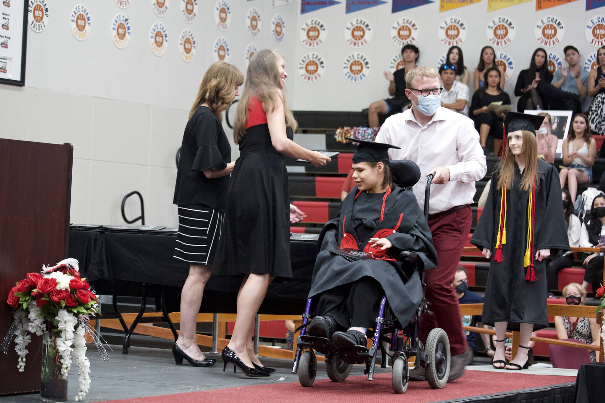 Mark Sabbatini / Juneau Empire 
Hannah Lynn Kadinger is wheeled across the stage after being the first senior to receive a diploma during the Juneau-Douglas High School: Yadaa.at Kalé graduation ceremony Sunday.