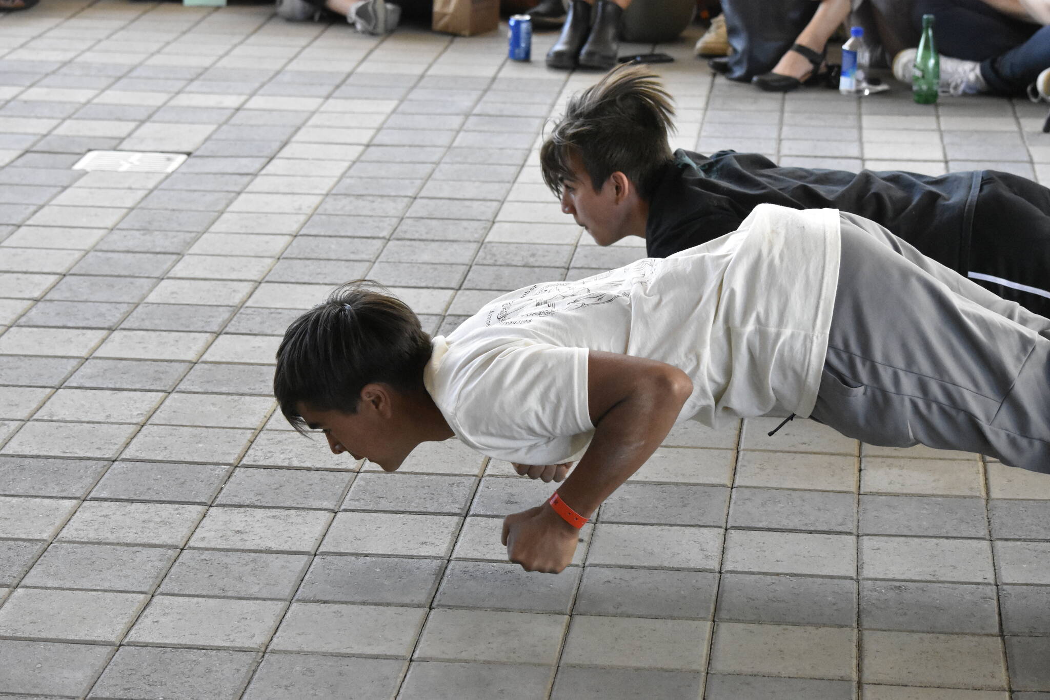 Nathan Blake, left, and Alex Marx-Beierly demonstrate a crawl meant to mimic the movements of a seal on an ice float during a demonstration of traditional games at the Sealaska Arts Campus on Thursday, June 8, 2022. (Peter Segall / Juneau Empire)