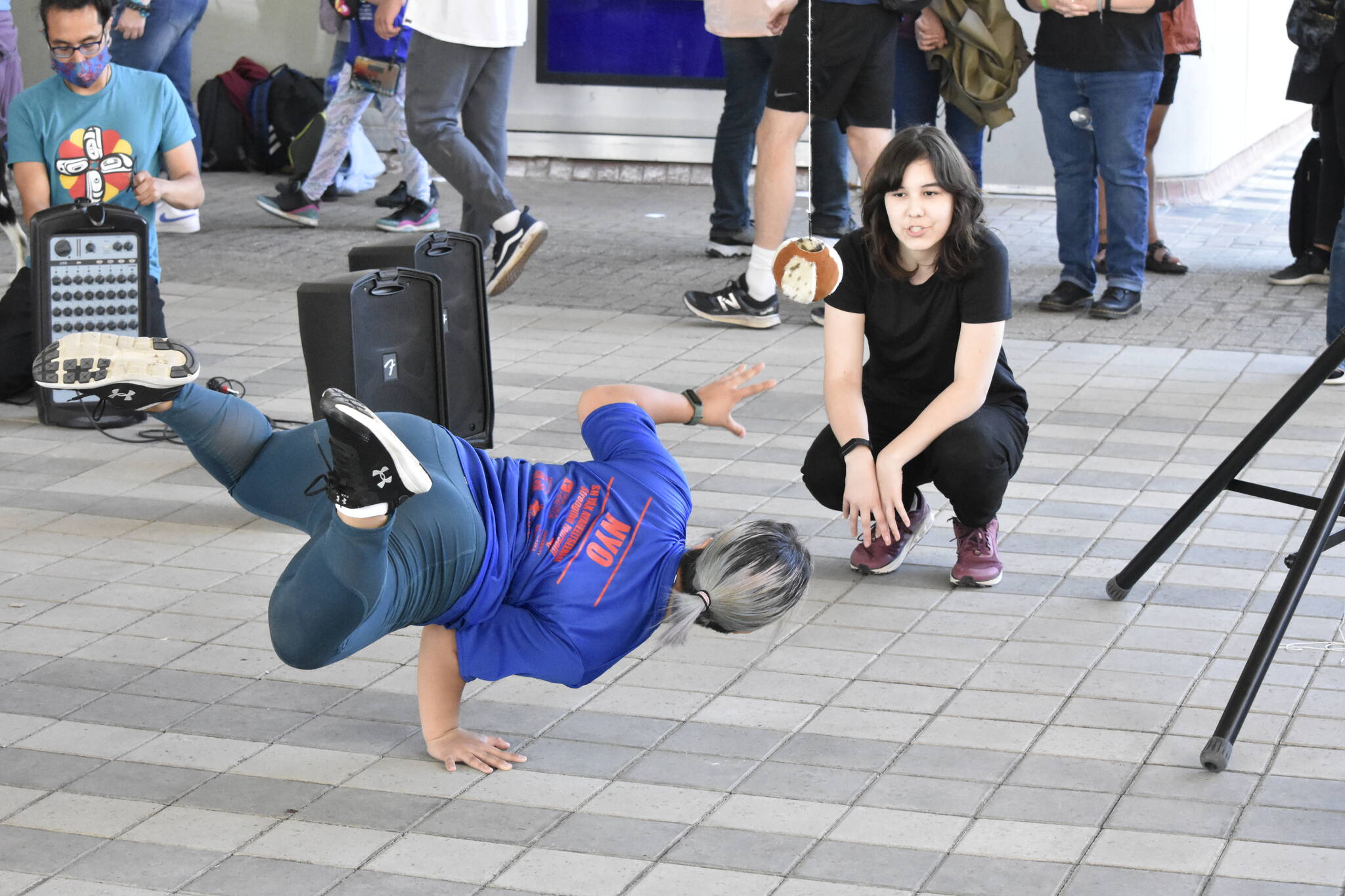 Lyric Ashenfelter attempts to grab a ball while balancing on her other hand while her traditional games teammate Simone Rabung watches during a demonstration of traditional Arctic games at the Sealaska Arts Campus on Thursday, June 8, 2022.