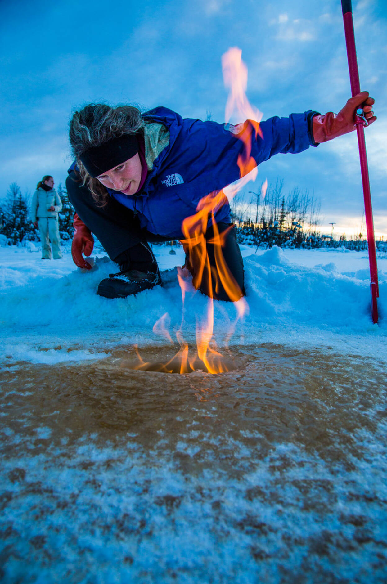 Courtesy Photo / Todd Paris, UAF 
Katey Walter Anthony inspects flaming methane gas seeping from a hole in the ice on the surface of a pond on the UAF campus in February 2016.