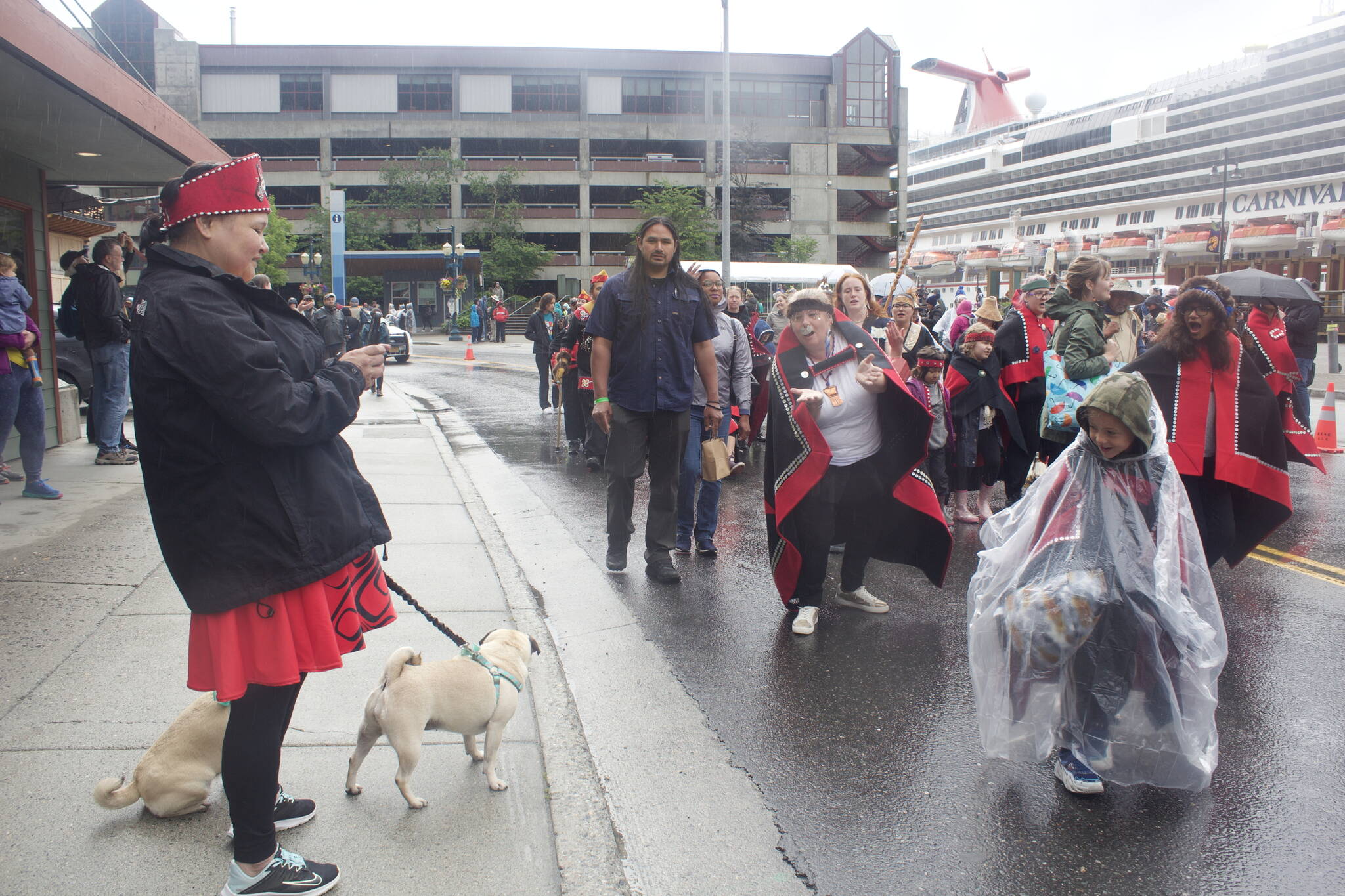 Mary Snook, a Ketchikan resident of Tlingit, Haida and Tsimshian ancestry, takes a photo of her fellow Alaska Natives passing by during the Celebration parade in downtown Juneau on Saturday morning. Snook said she usually participates in the parade when visiting for the landmark biennial gathering, but too many members of her community’s dance group were unable to make it this year due to reasons related to the COVID-19 pandemic. (Mark Sabbatini / Juneau Empire).