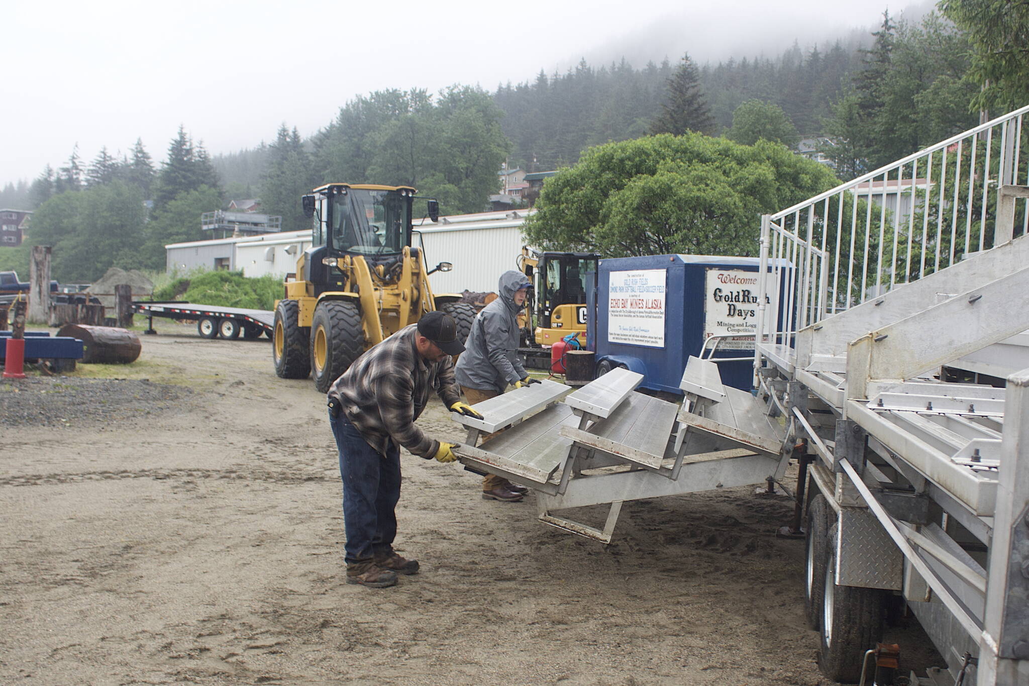 Eddie Petries, foreground, a participant in Juneau Gold Rush Days since the 1990s, and Darren Hershman, a Coeur Alaska Inc. mining intern from Fairbanks, lower a set of bleacher seats at Savikko Field on Monday in preparation for the events that begin Saturday. Gold Rush Days is celebrating its 30th year after making its debut in 1990 and missing two years during the pandemic. (Mark Sabbatini / Juneau Empire)