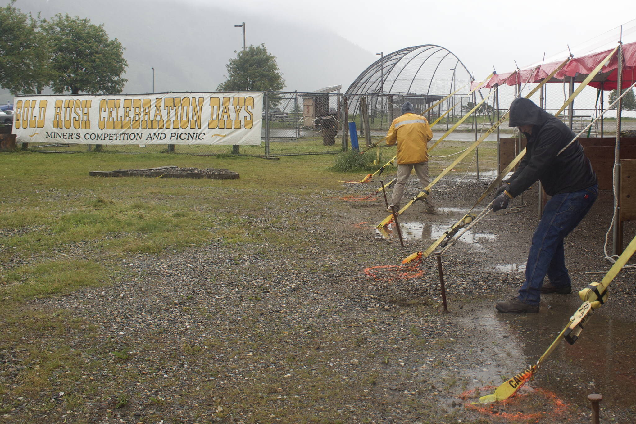 Gabe Holst, foreground, a Coeur Alaska Inc. mining intern from Springfield, Missouri, tightens an anchor rope on a shelter tent at Savikko Field on Monday where vendors will be during Juneau Gold Rush Days. (Mark Sabbatini / Juneau Empire)