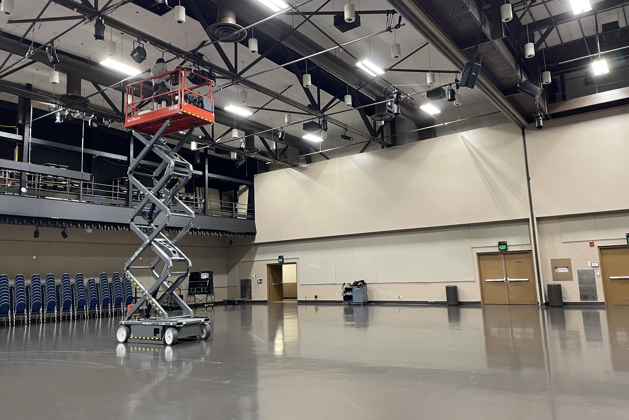 Centennial Hall crewmember Dylan Taylor, atop the lift, prepares equipment for GLITZ, which returns to the hall this weekend, on June 15, 2022. (Michael S. Lockett / Juneau Empire)