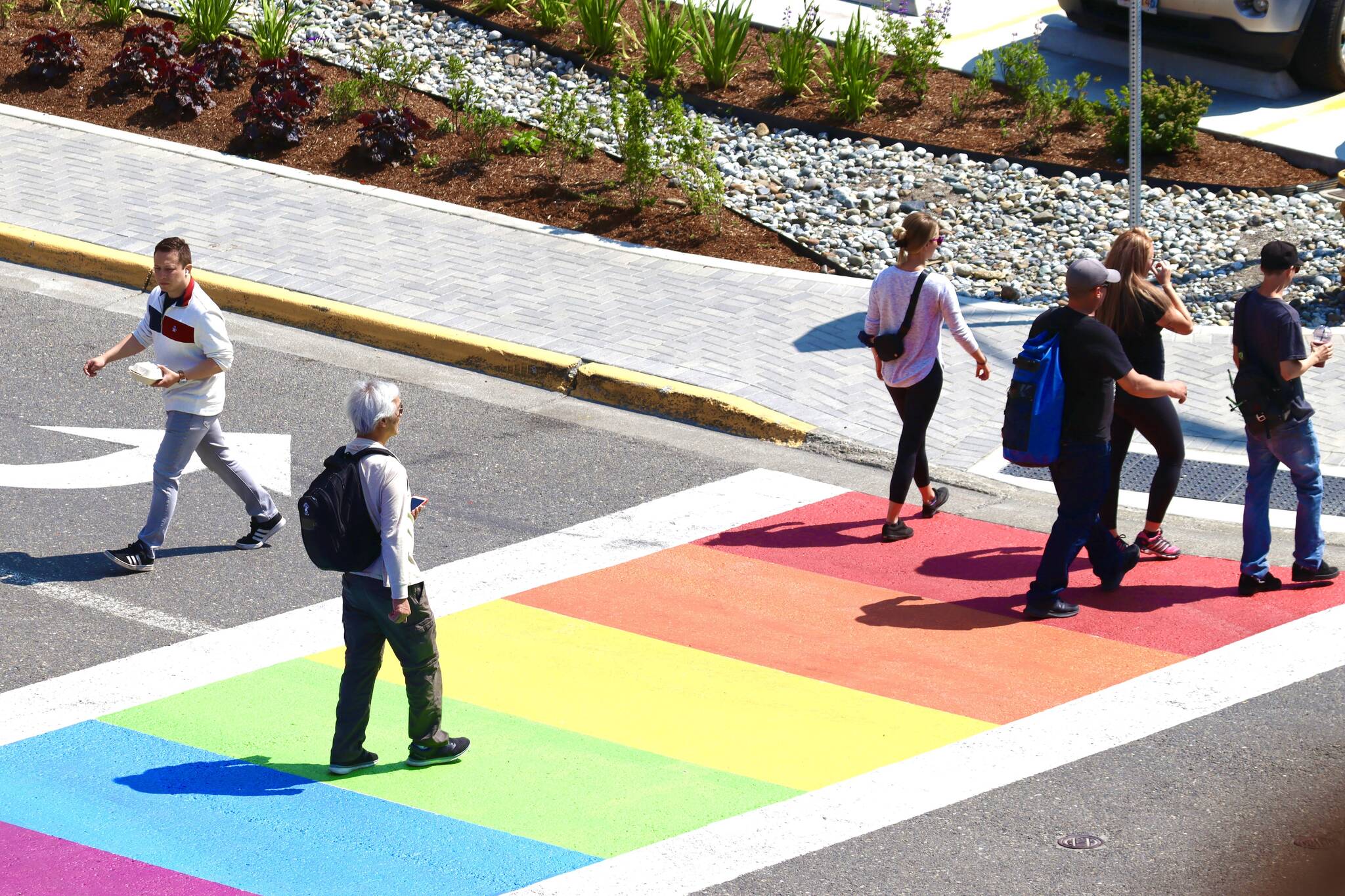 Pedestrians cross the newly repainted rainbow sidewalk downtown on Thursday, June 16, 2022. Painting of the crosswalk was delayed by supply chain issues. (Michael S. Lockett / Juneau Empire)