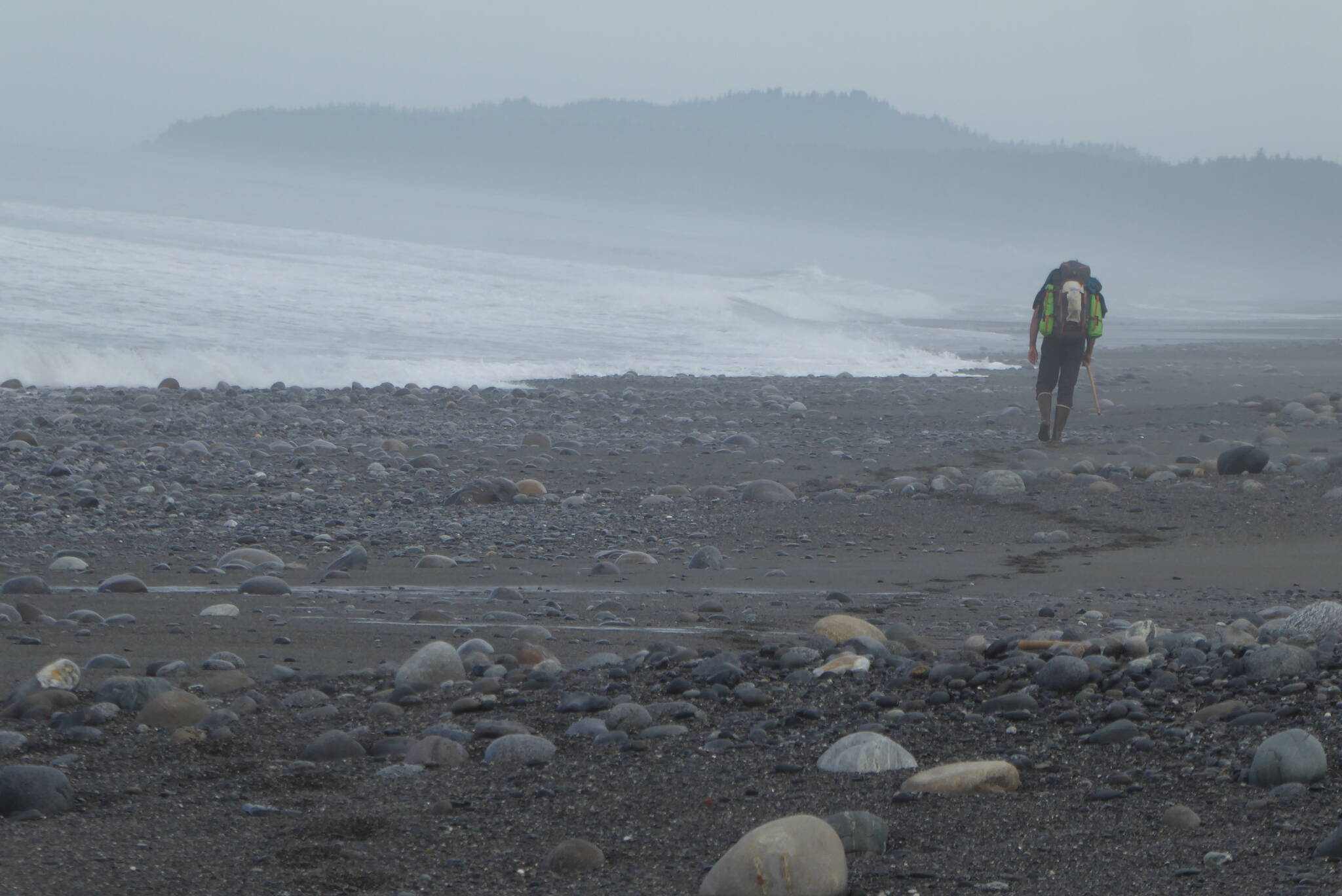 A scientist with a heavy backpack hikes the Lost Coast north of Lituya Bay to reach his study areas. (Courtesy Photo / Ned Rozell)
