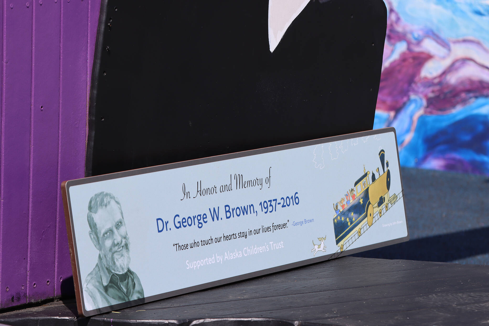 A plaque honoring Dr. George Brown was installed Saturday in Juneau’s Project Playground. The train on the plaque was created by John Brown, George Brown’s brother. John Brown traveled from Texas to attend the event. (Ben Hohenstatt / Juneau Empire)