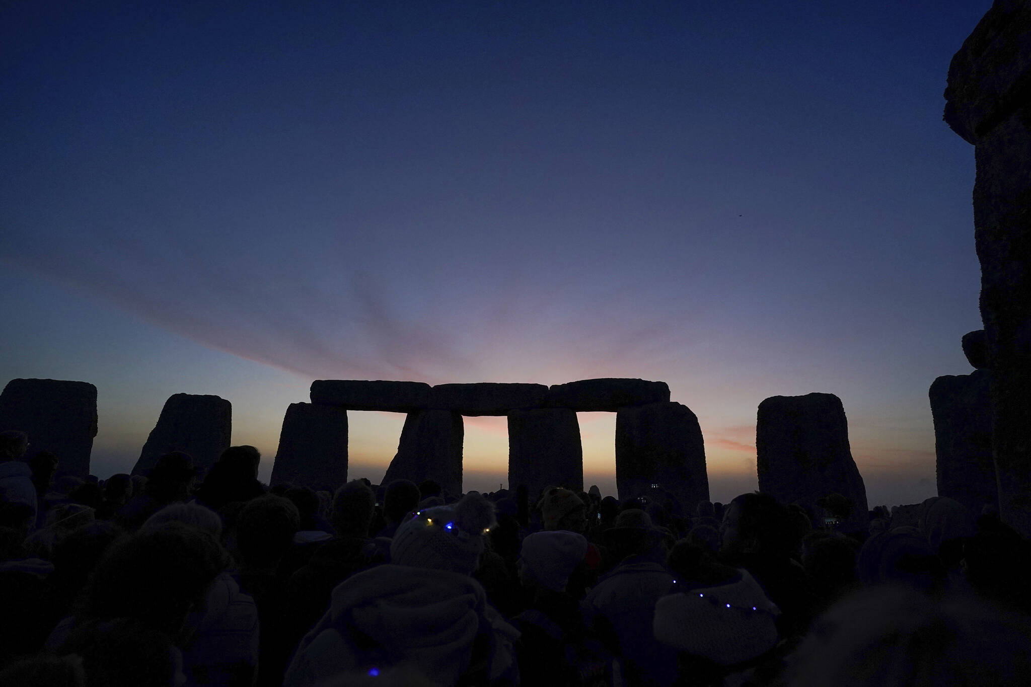 Dawn breaks behind the stones during the Summer Solstice festivities at Stonehenge in Wiltshire, England, Tuesday, June 21, 2022. After two years of closure due to the COVID-19 pandemic, Stonehenge reopened Monday for the Summer Solstice celebrations. (Andrew Matthews/PA via AP)