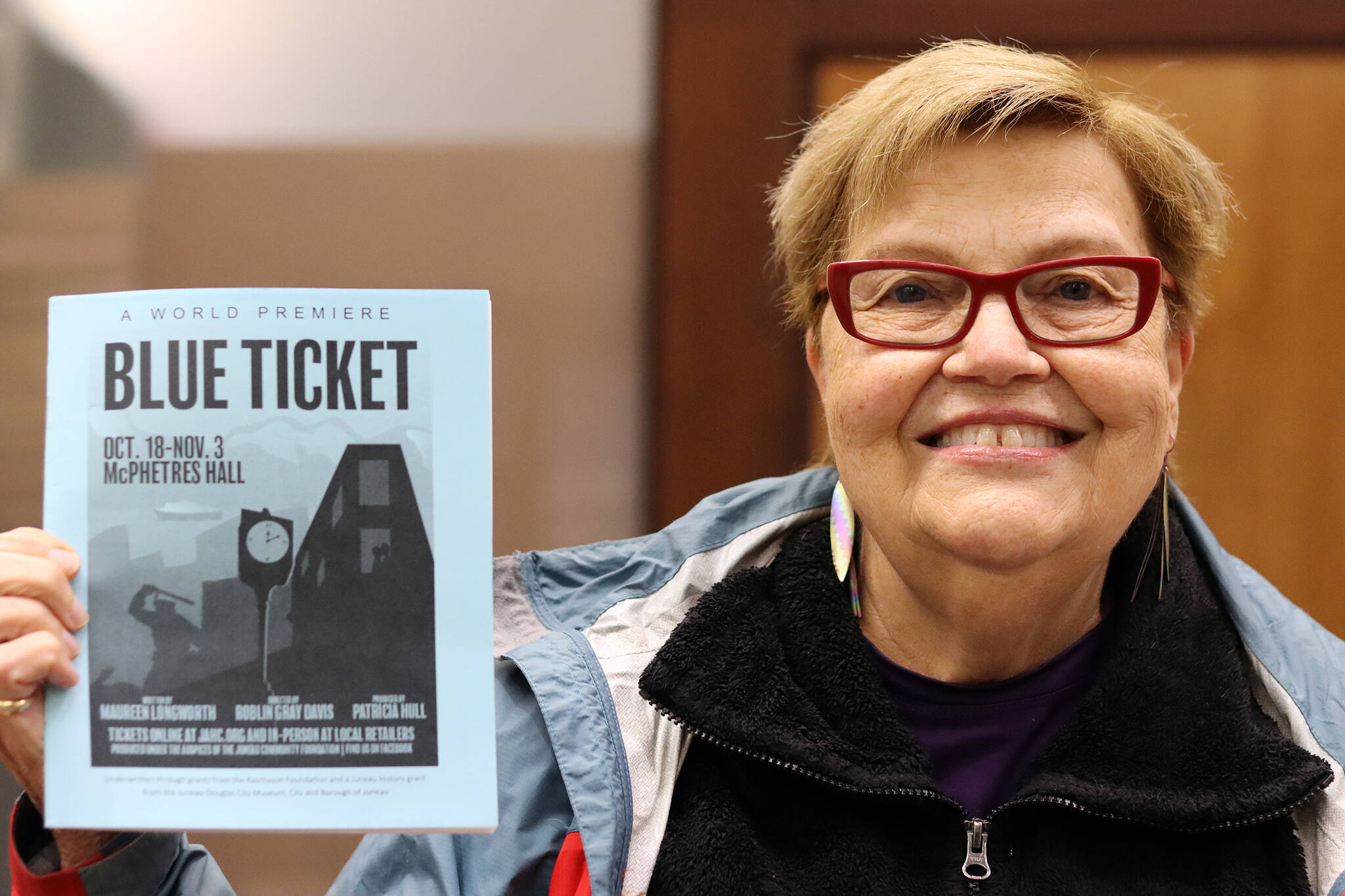 Clarise Larson / Capital City Weekly
Playwright Maureen Longworth holds up a playbill for “Blue Ticket.” The play, which tells a story inspired by stories from Juneau’s past shared with Longworth, is making its on-screen debut during Pride Month. The play debuted on stage in 2019.