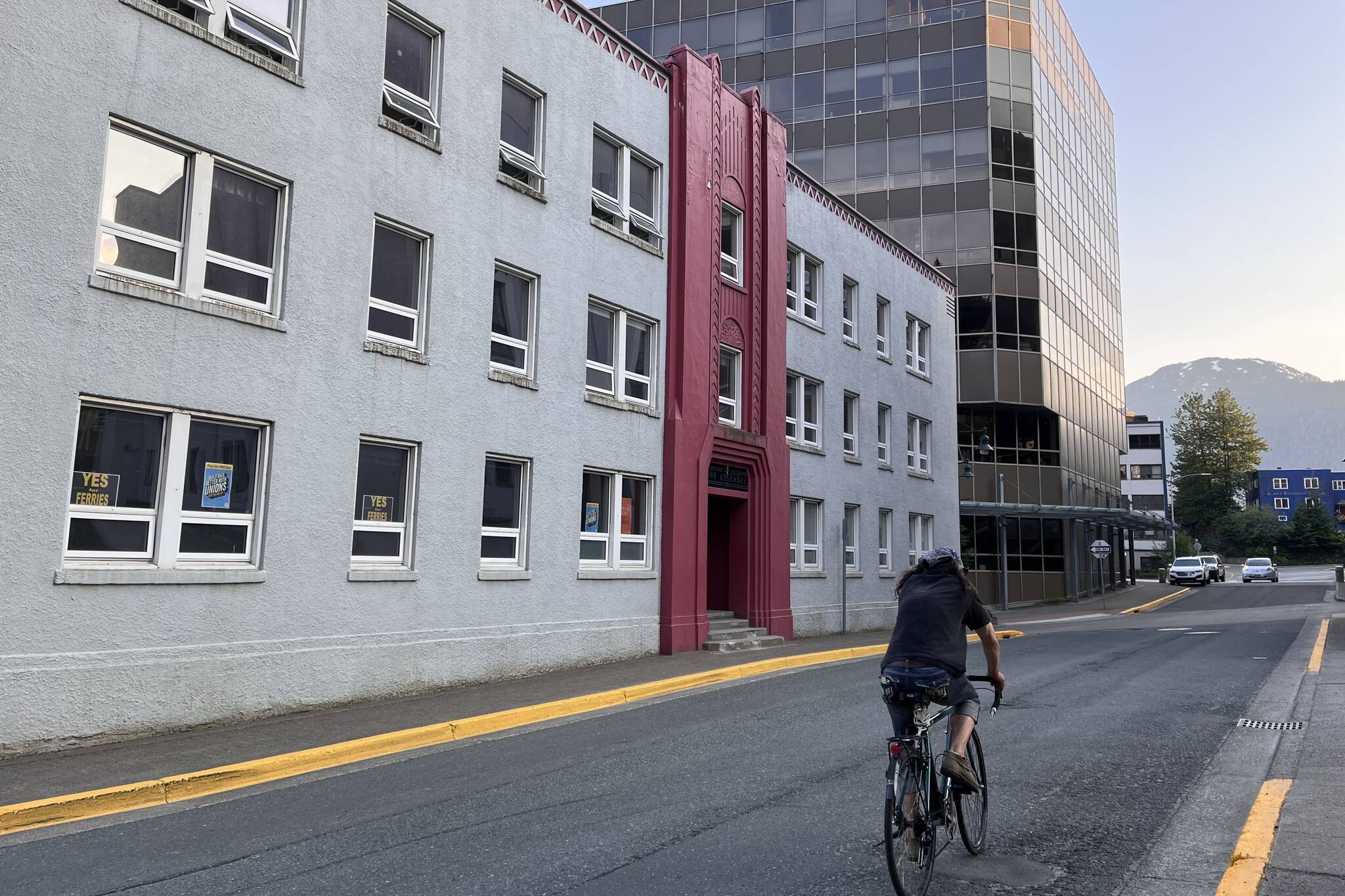 A man bikes past the Assembly Building, located just across the street from the Alaska State Capitol. The building is set to be renovated into a 33-unit multi-family apartment complex to house legislative staff. (Clarise Larson /Juneau Empire)