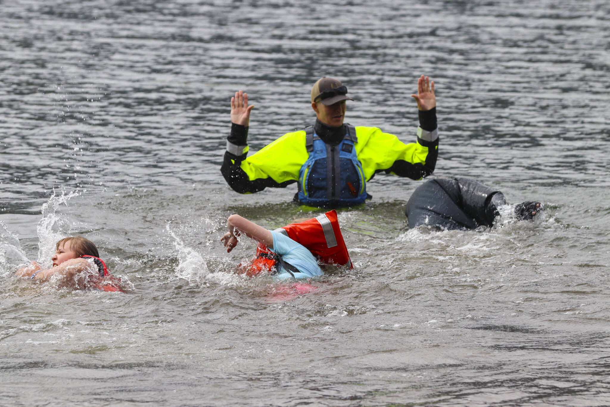 Kids wearing a variety of personal flotation devices swim to Coast Guard Lt. J.J. Cestero as part of a boating safety class in Twin Lakes on June 30, 2022. (Michael S. Lockett / Juneau Empire)