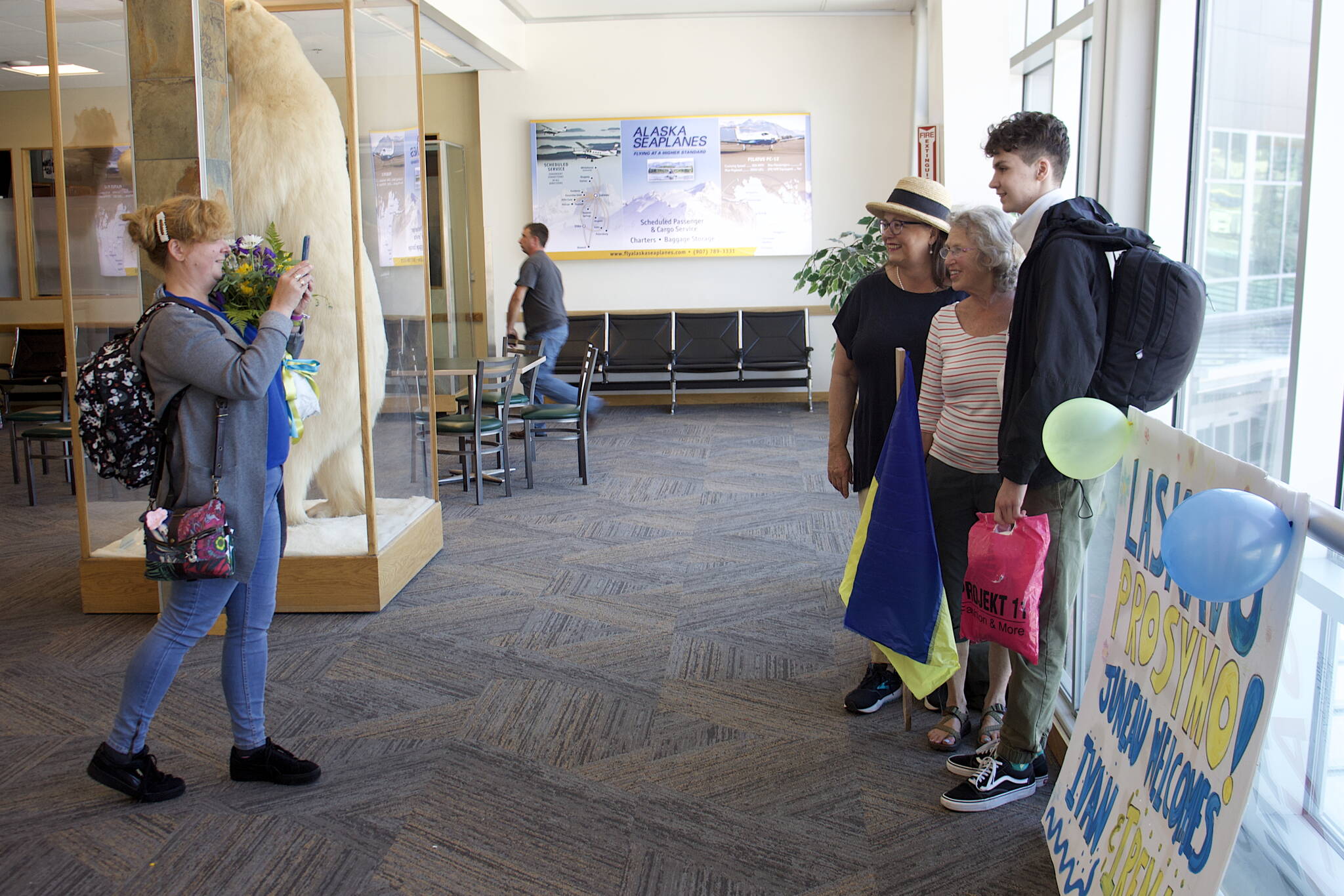 Bridget Smith, left, takes a photo of Iryna Hrynchenko, her 18 year old son Ivan and Joyanne Bloom inside Juneau Airport on Saturday. (Mark Sabbatini / Juneau Empire)