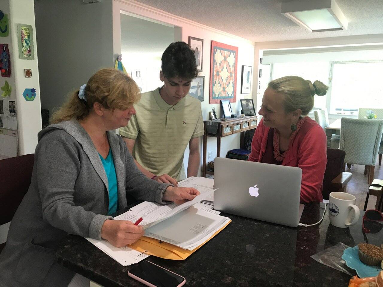 Heather Parker, right a Sponsor Circles member, helping Iryna and Ivan Hrynchenko with paperwork after the Ukrainian mother and son arrived in Juneau last Saturday. Five local residents formed a local chapter of Social Circles, a nationwide organization working to resettle refugees from Afghanistan and Ukraine in the U.S. (Courtesy Photo / Joyanne Bloom)