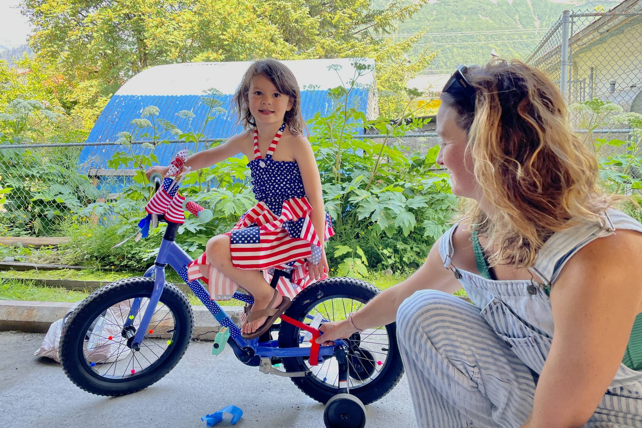 Sayler Williams, left, poses with her freshly decorated bike as Abby Williams looks on during the Douglas Fourth of July Committee’s annual Bicycle Decorating session held at the Douglas Public Library on July 2, 2022. (Michael S. Lockett / Juneau Empire)