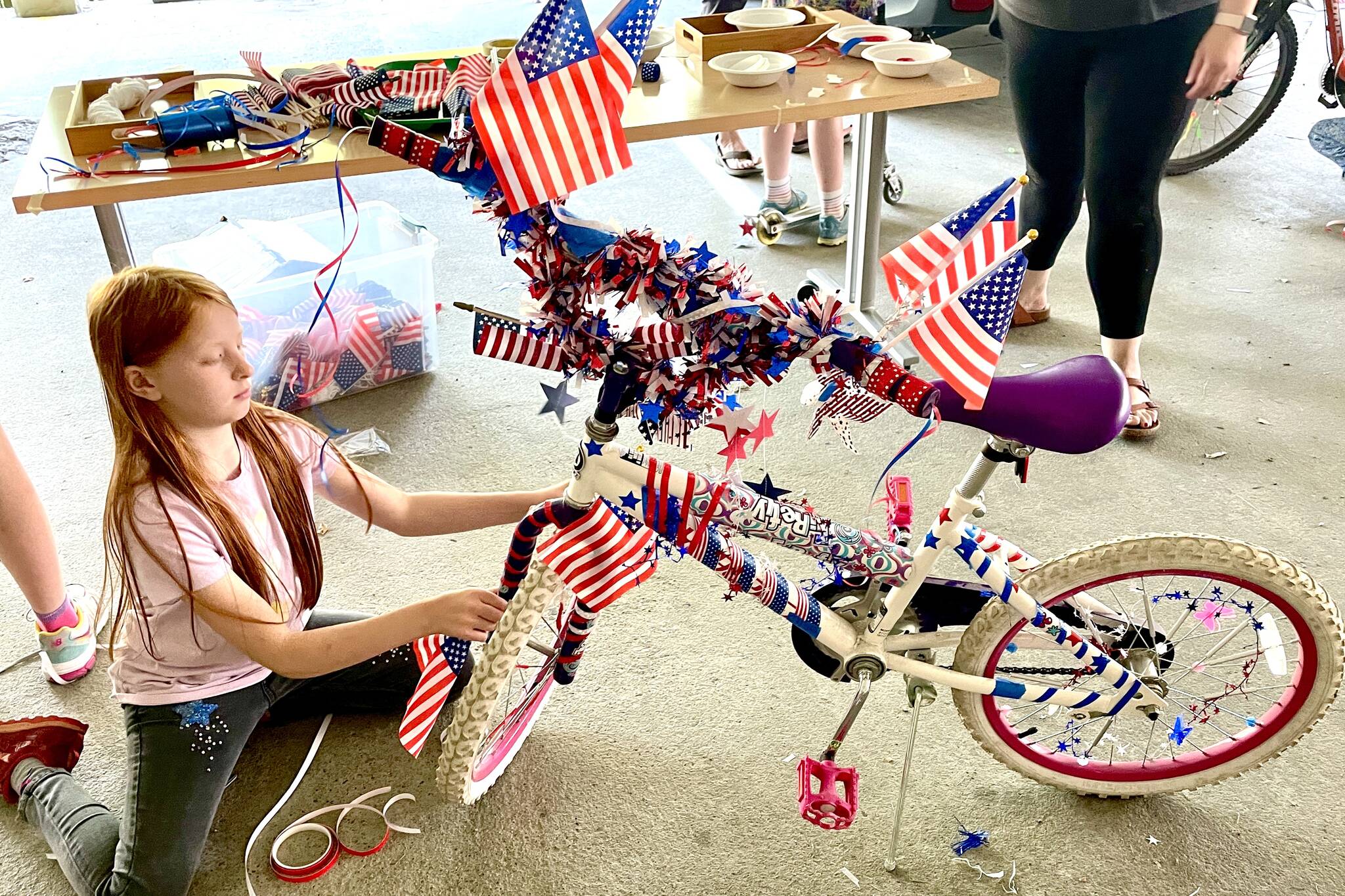 Aoibhinn Reetz executes her creative vision for her bike during the Douglas Fourth of July Committee’s annual Bicycle Decorating session held at the Douglas Public Library on July 2, 2022. (Michael S. Lockett / Juneau Empire)
