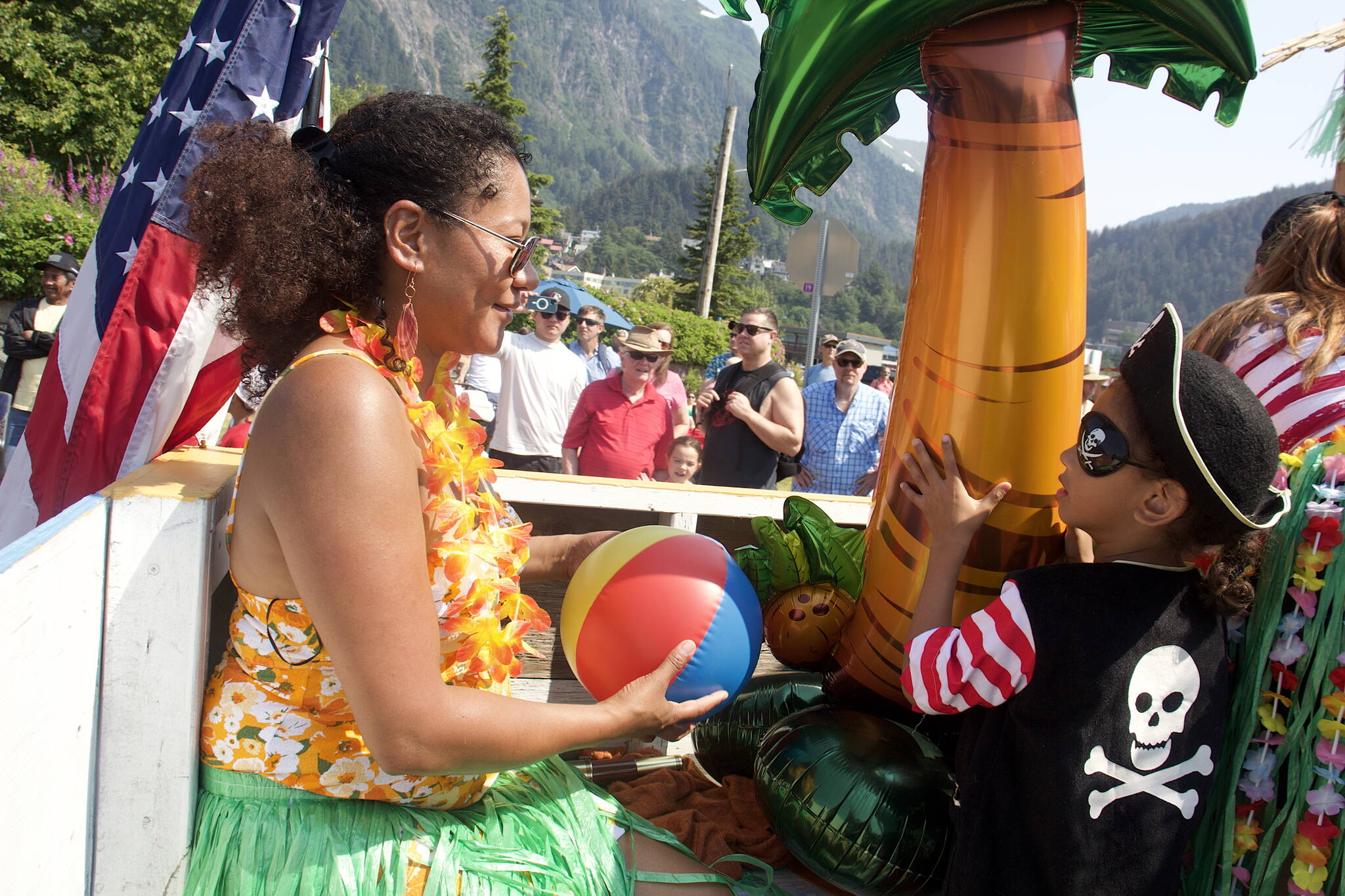 Rachel Hurst hands her son Benjamin, 4, a beach ball to throw to the crowd from the Hawaiian-themed Juneau Urgent Care float during the July 4 parade in downtown Juneau. (Mark Sabbatini / Juneau Empire)
