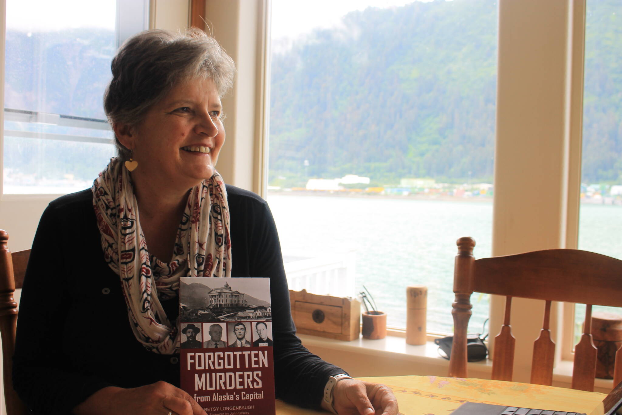Betsy Longenbaugh sits at the table she spent the majority of her time writing her debut book, “Forgotten Murders from Alaska’s Capital” which recounts 10 long-forgotten murders that occurred in the Juneau-Douglas area between 1902 and 1959. (Clarise Larson / Juneau Empire)