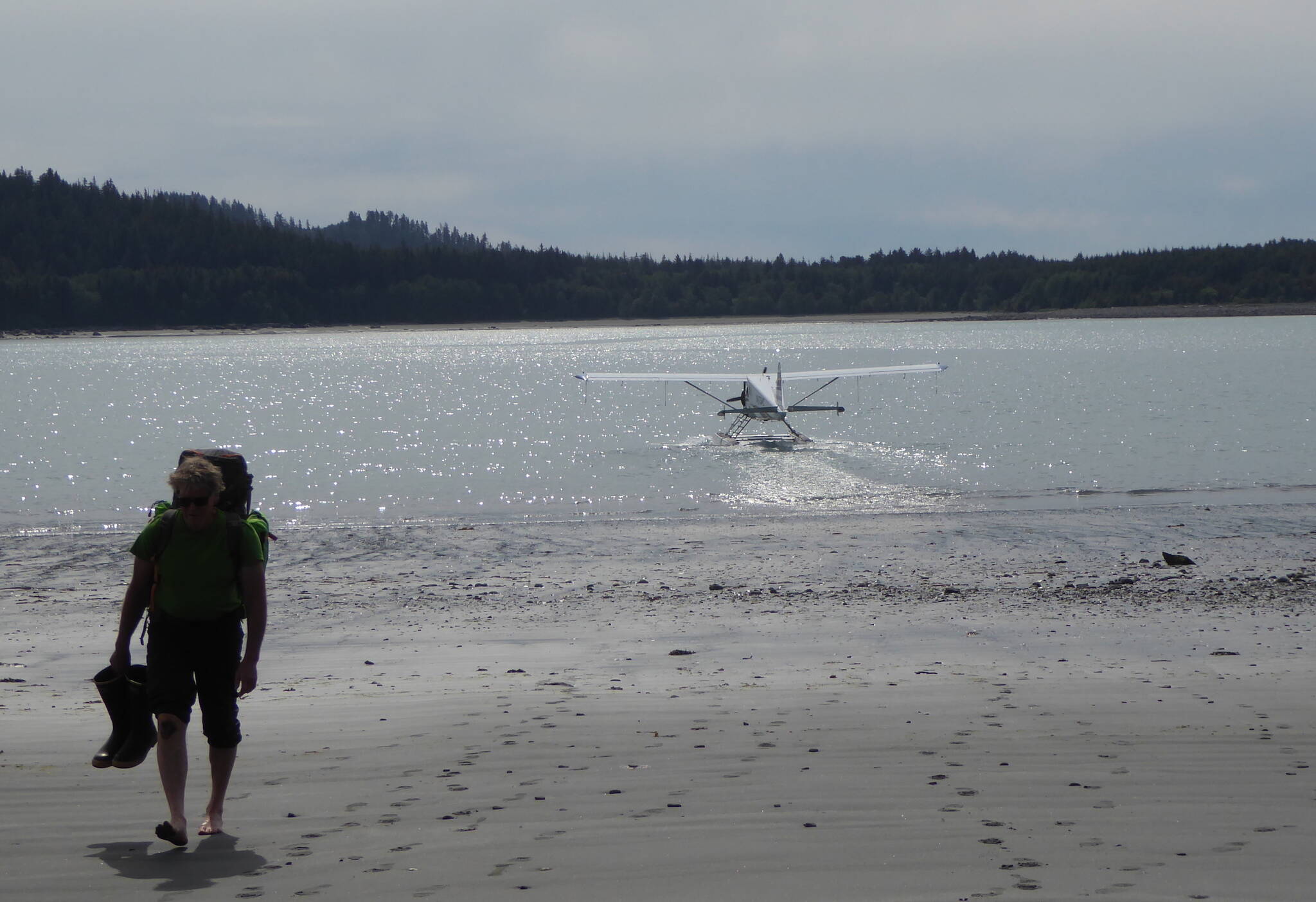 Dan Mann walks from a float plane in Anchorage Cove of Lituya Bay in Southeast Alaska. The pilot had just dropped him off for a 12-day trip. (Courtesy Photo / Ned Rozell)
