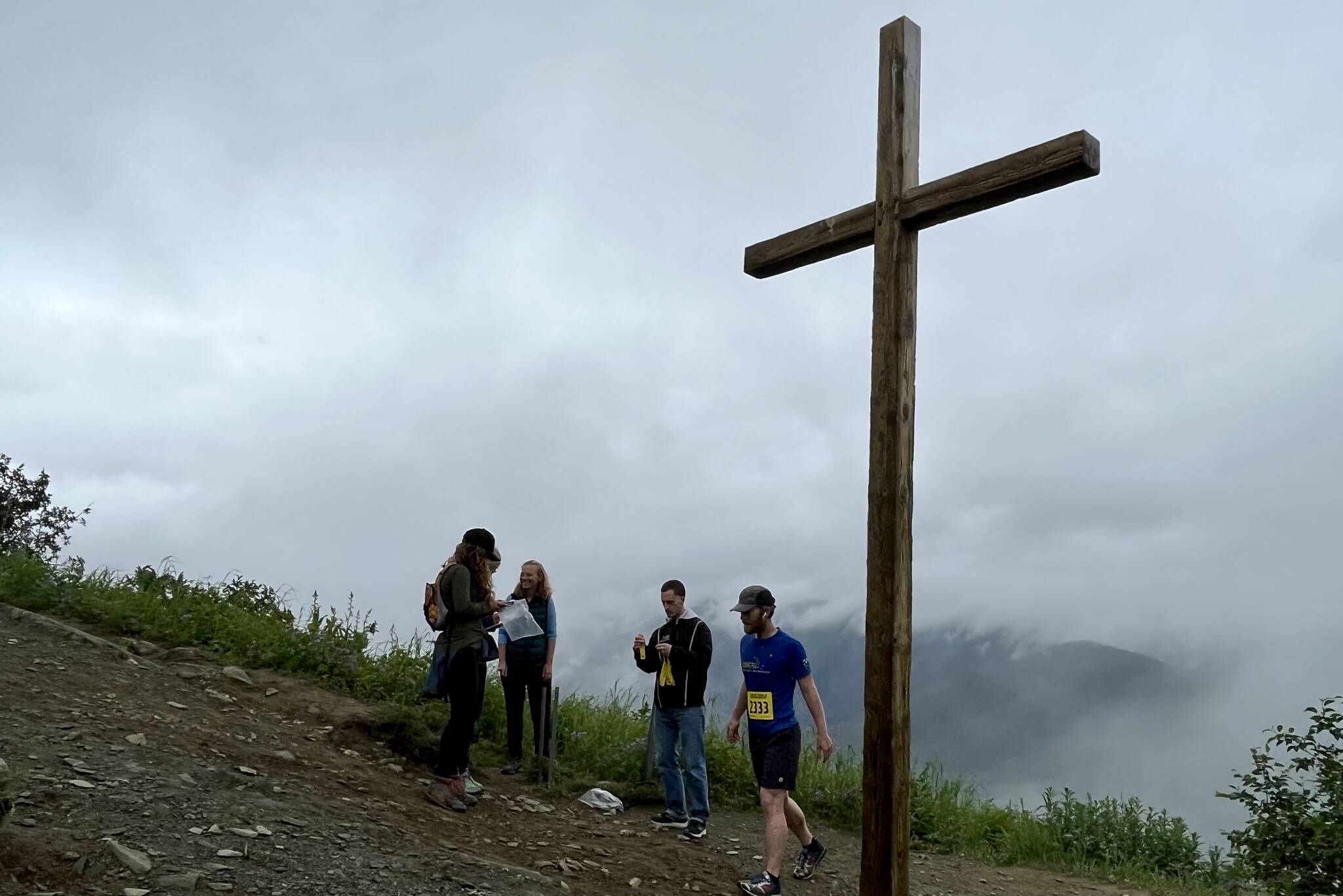 Juneau resident Quinn Tracy tags Father Browns Cross to receive his time from Juneau Trail and Road Runners volunteers. Tracy won the virtual race in 2021. (Jonson Kuhn / Juneau Empire)