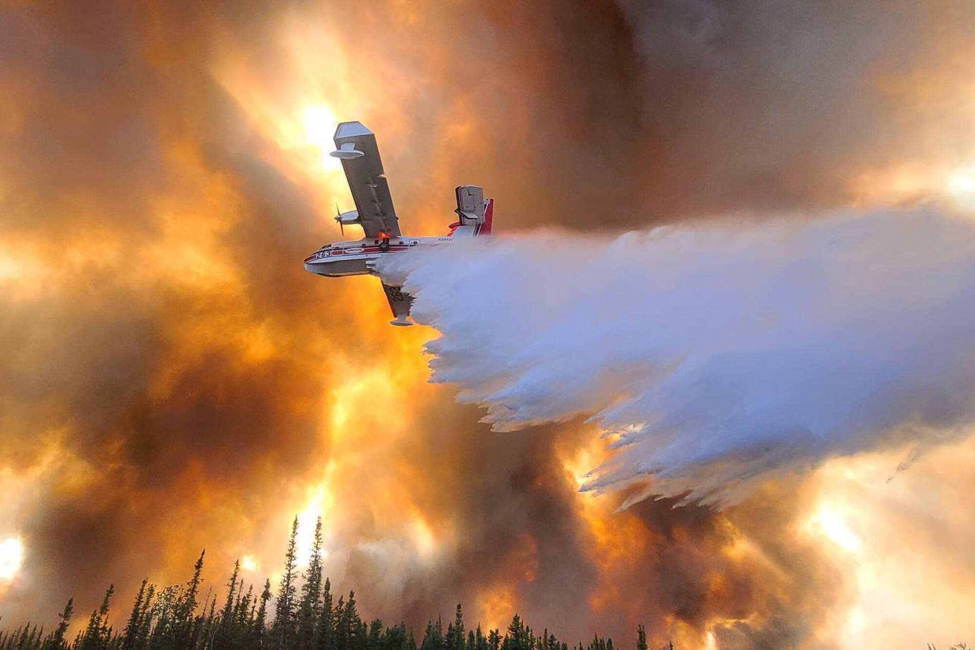 In this photo provided by Eric Kiehn, Northwest Incident Management Team 10, Alaska Division of Forestry, a fixed-wing aircraft drops water on the Clear Fire near Anderson, Alaska, on July 6, 2022. Alaska’s remarkable wildfire season includes over 530 blazes that have burned an area more than three times the size of Rhode Island, with nearly all the impacts, including dangerous breathing conditions from smoke, attributed to fires started by lightning. (Eric Kiehn, Northwest Incident Management Team 10, Alaska Division of Forestry)
